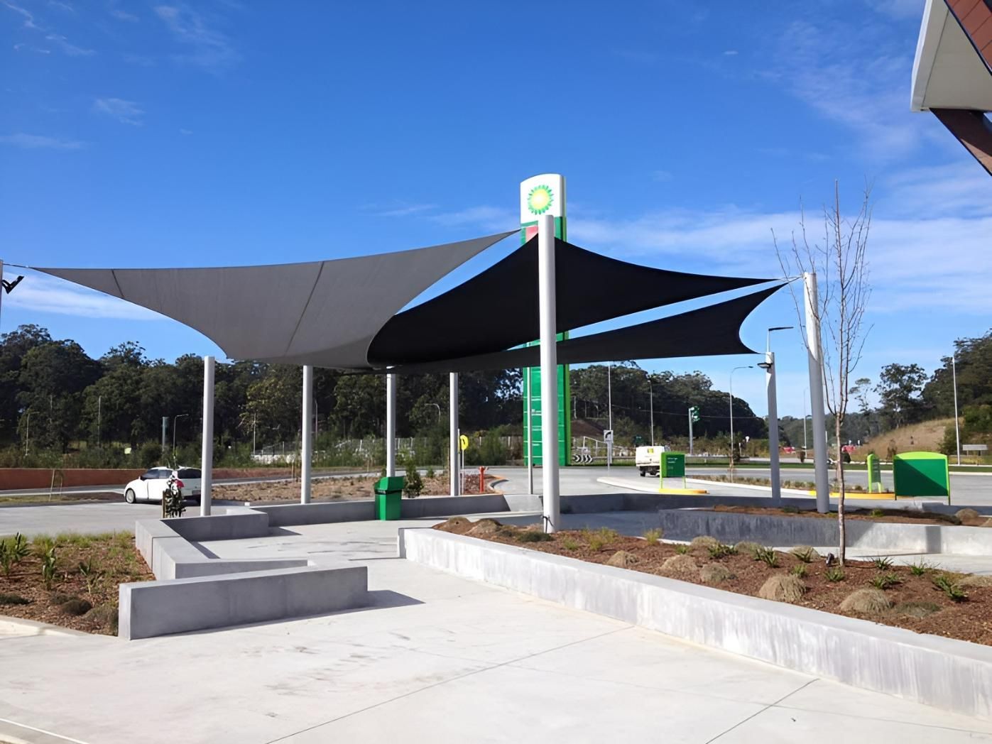 A Car Is Parked Under an Umbrella in Front of A Bp Gas Station — Jon Wilson Canvas & Shade in Coffs Harbour, NSW