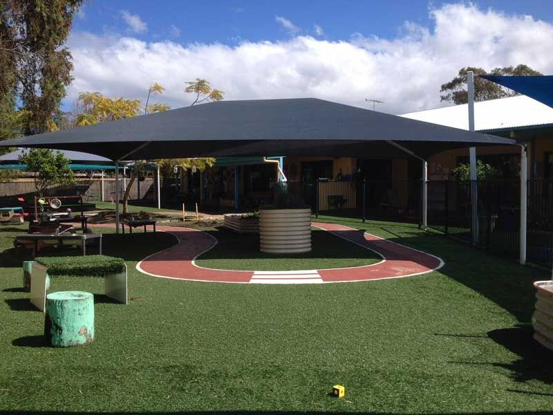 A Large Umbrella Is Sitting on Top of A Lush Green Field — Jon Wilson Canvas & Shade in Coffs Harbour, NSW