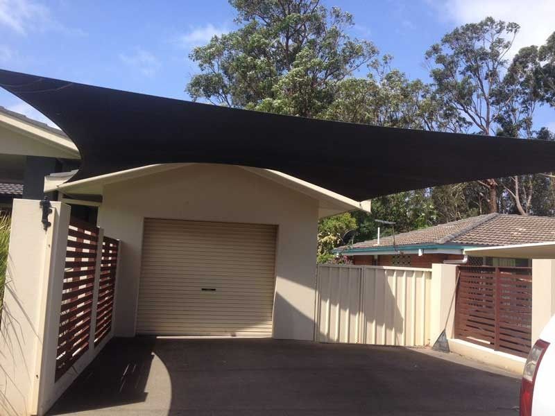 A Car Is Parked Under an Umbrella in Front of A Garage — Jon Wilson Canvas & Shade in Coffs Harbour, NSW