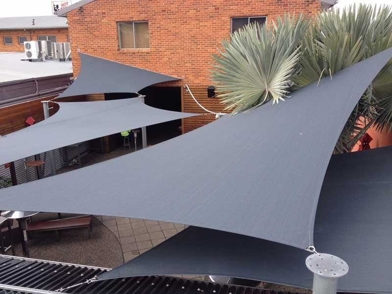 A Group of Umbrellas Are Sitting in Front of A Brick Building — Jon Wilson Canvas & Shade in Coffs Harbour, NSW