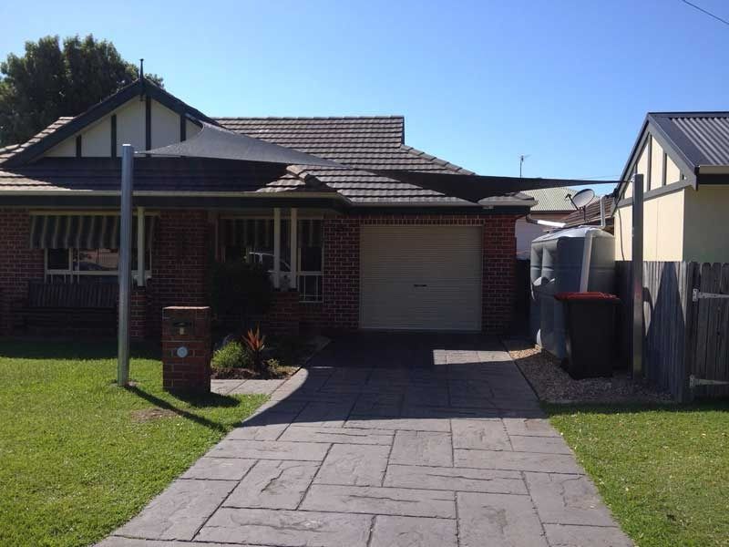 A Driveway Leading to A Brick House with A White Garage Door — Jon Wilson Canvas & Shade in Coffs Harbour, NSW