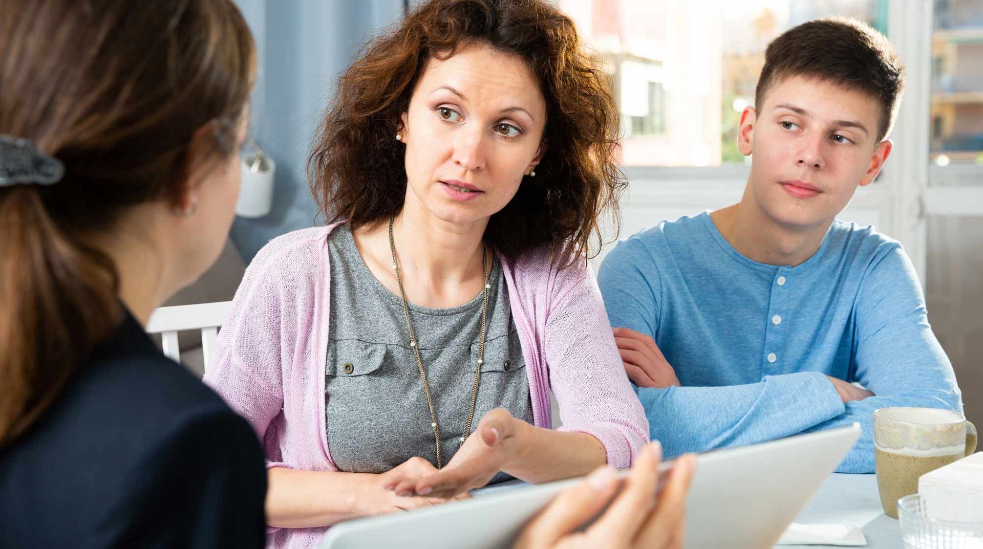 A woman is talking to a man and a woman while sitting at a table. The Role of Parents in the College Search Process