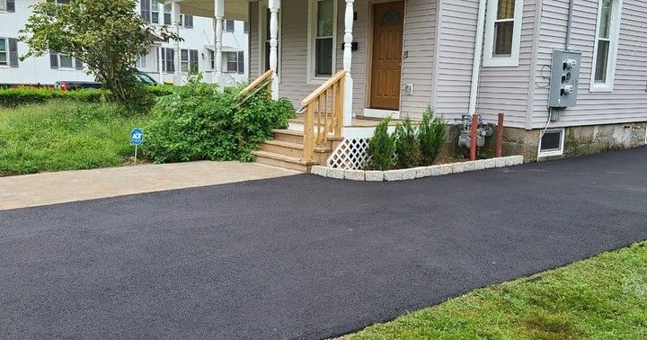 A driveway leading to a house with a porch and stairs.