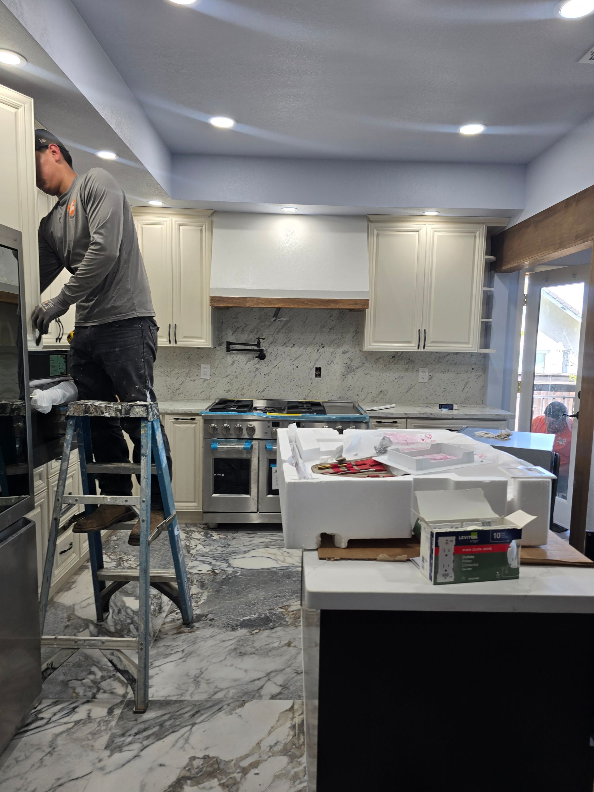 Person standing on a ladder working in a modern kitchen under renovation