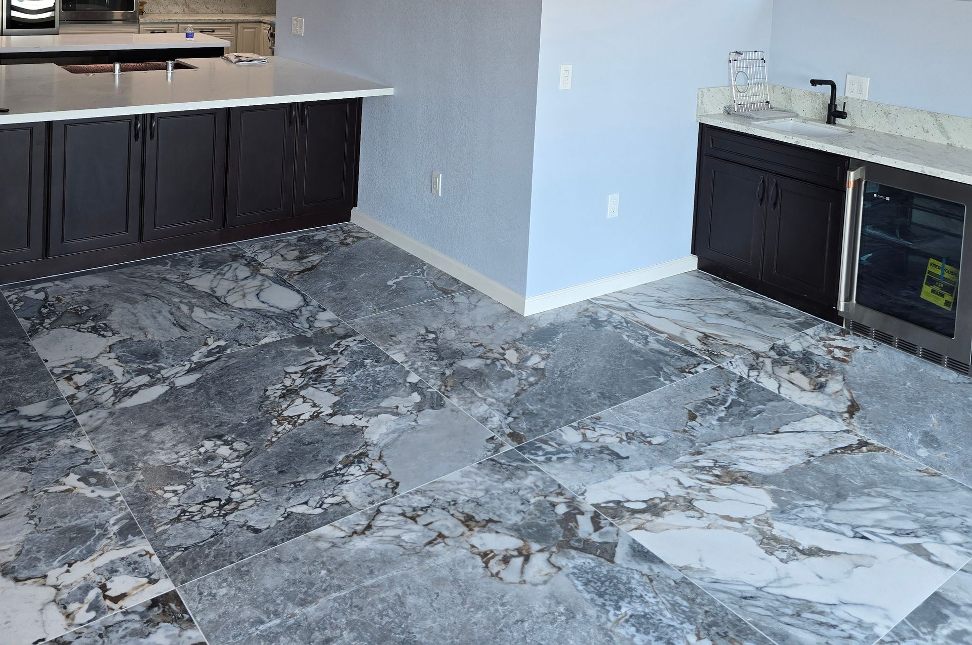 Kitchen with dark cabinets and a gray marble-patterned floor in progress
