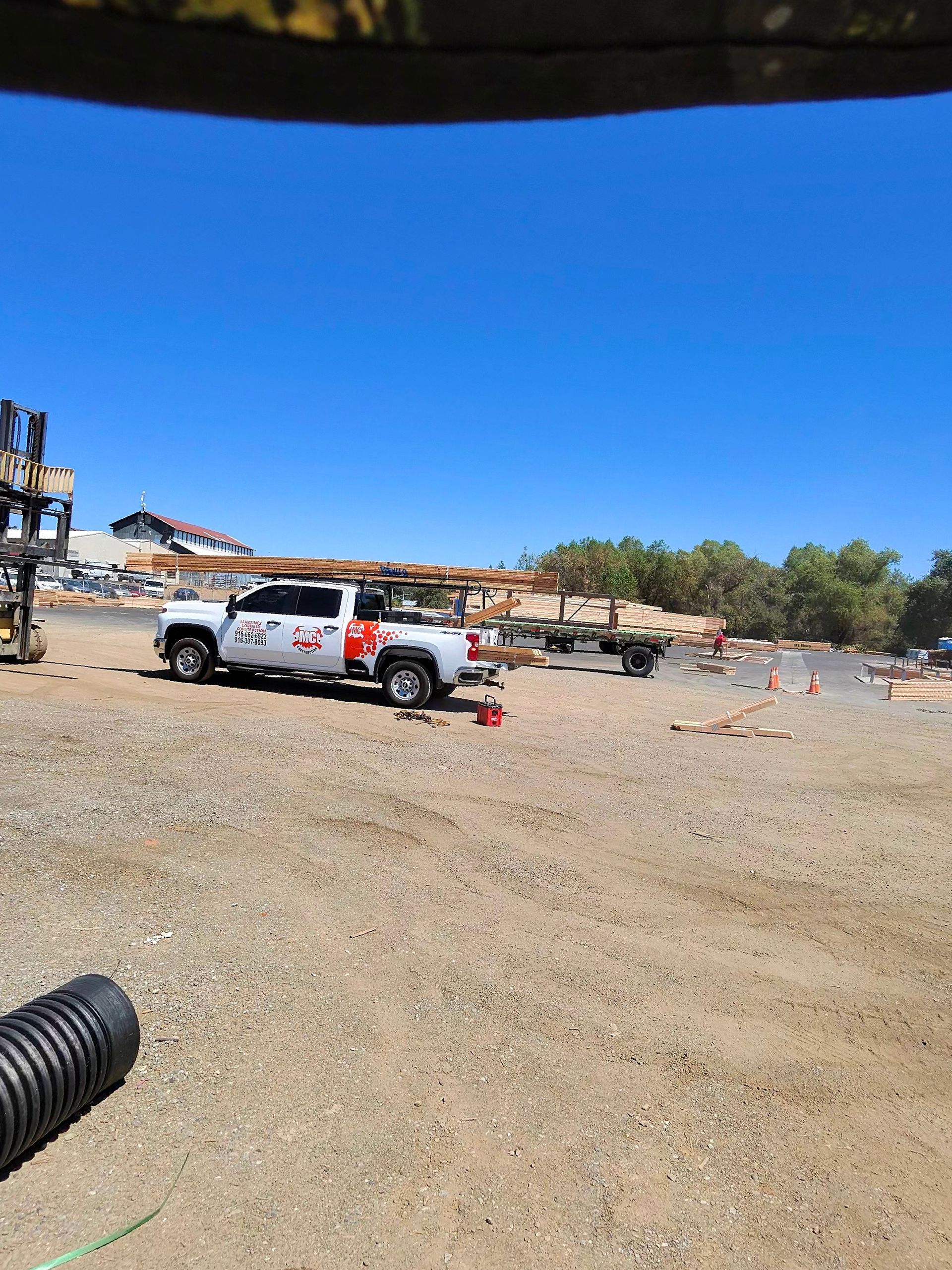 White pickup truck on a gravel lot with cones and people, under a bright blue sky