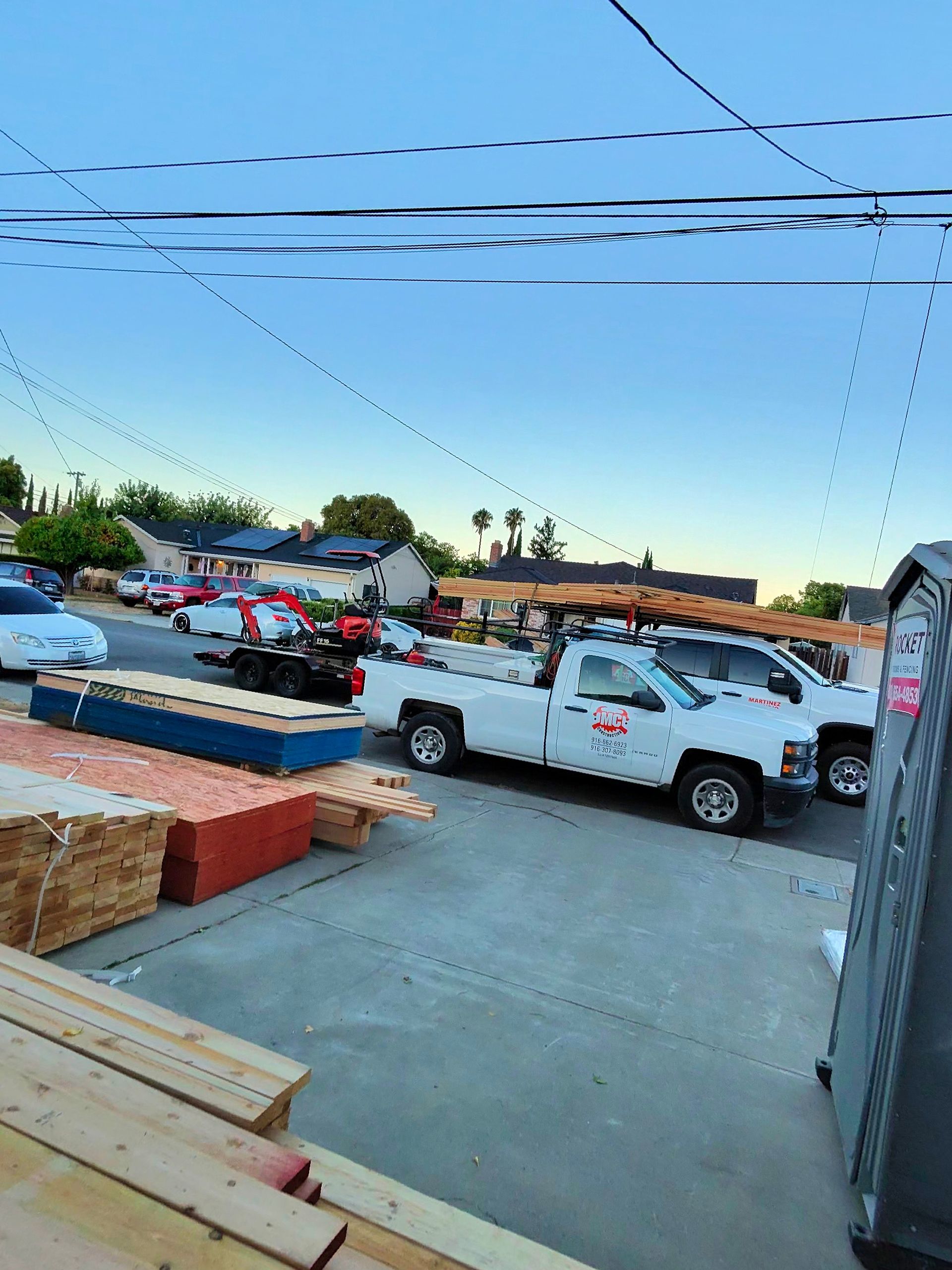 Construction site with trucks and lumber under a clear blue sky at sunset