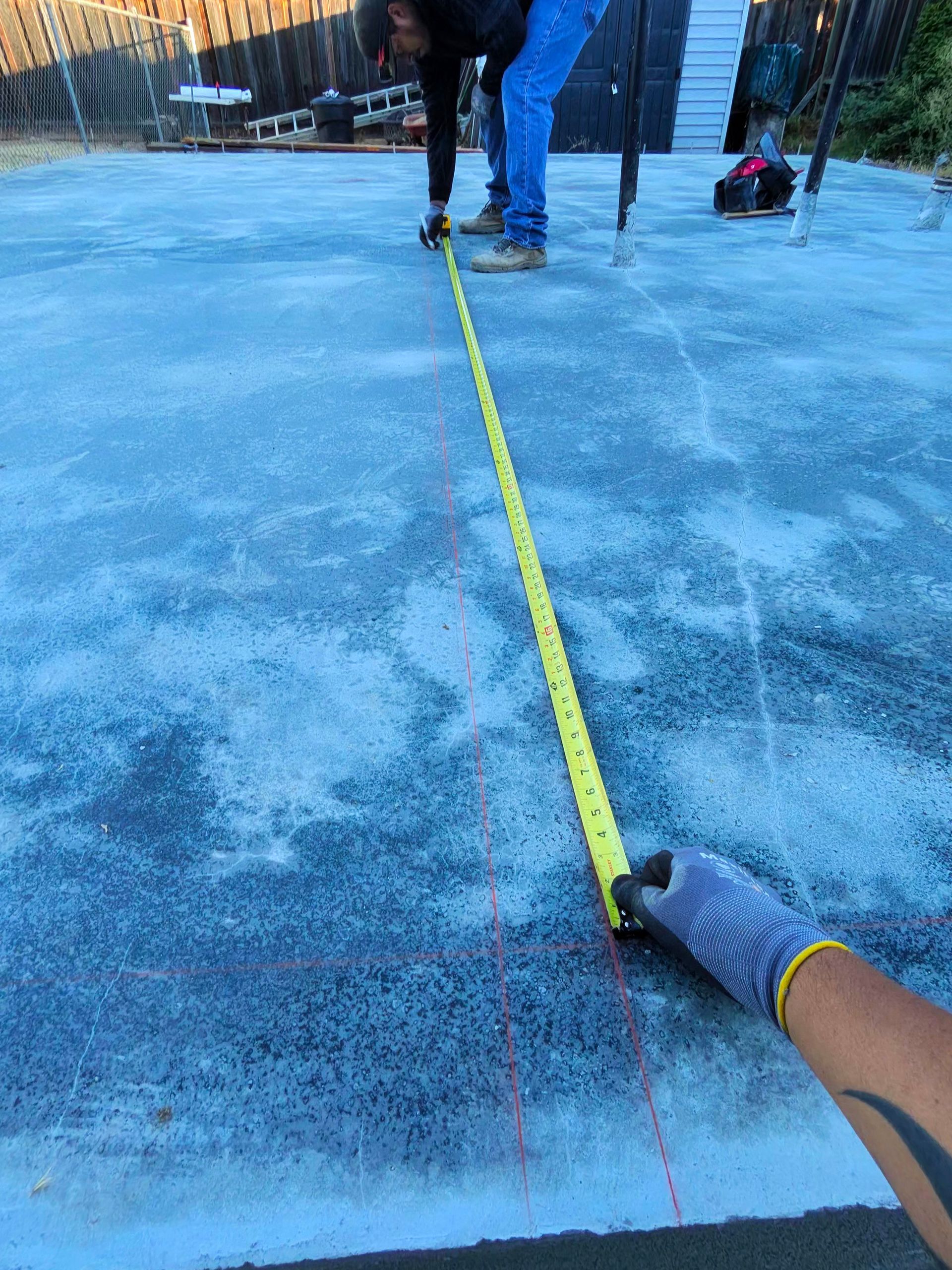 People measuring a blue icy surface with a yellow tape measure outdoors