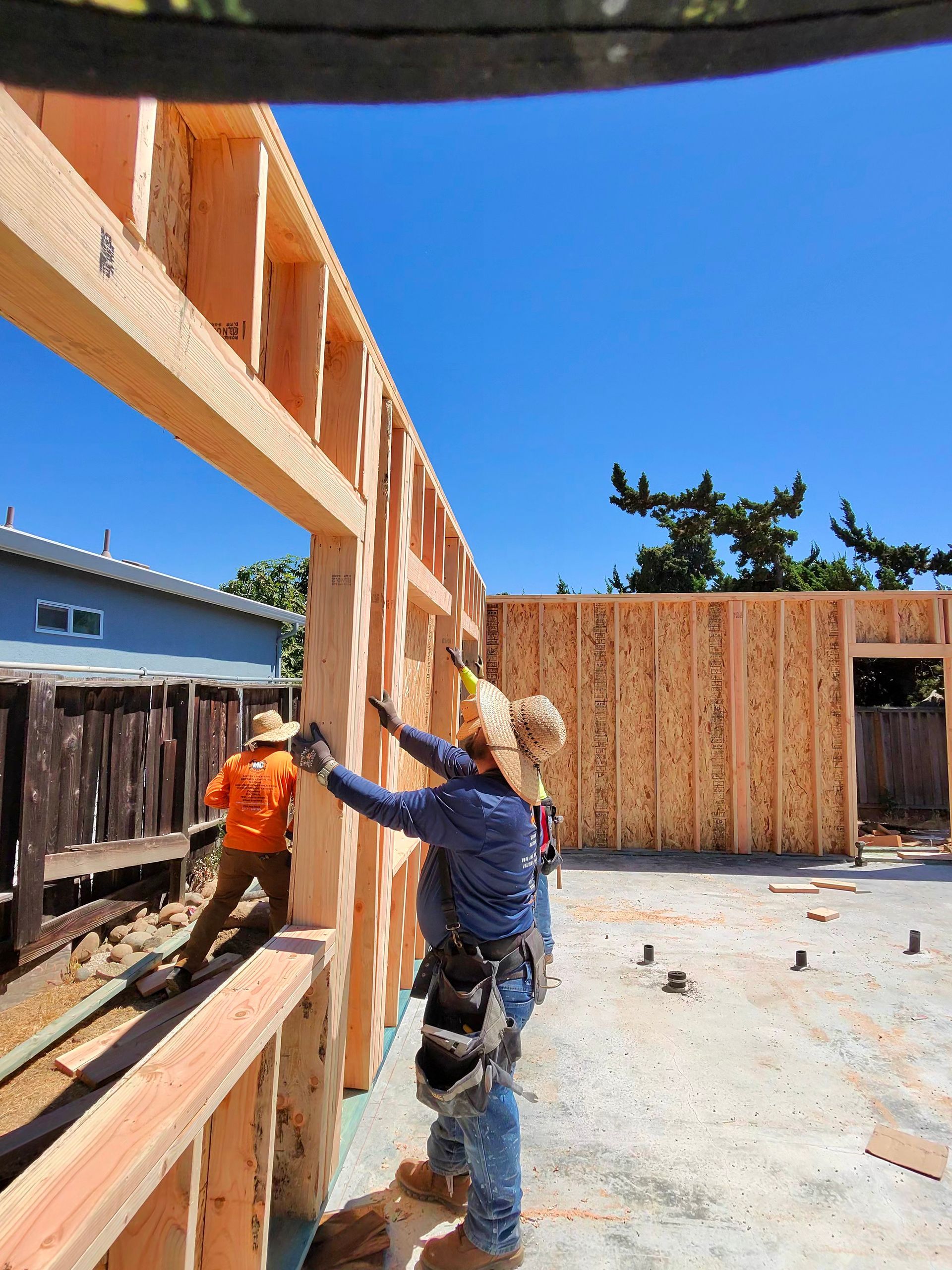 Two construction workers framing a house wall on a sunny building site