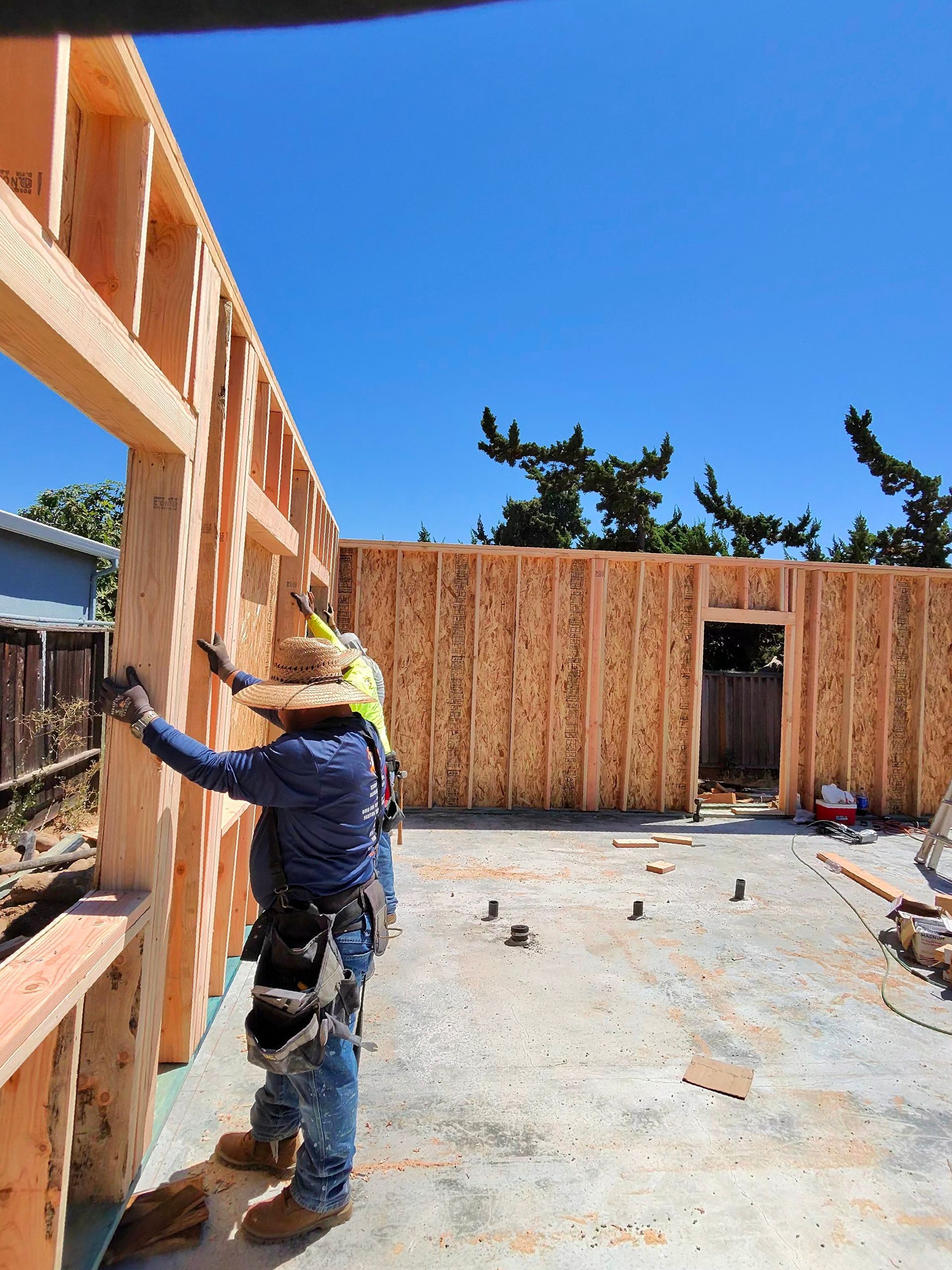 Worker installing wall framing in a wooden house under construction on a sunny day