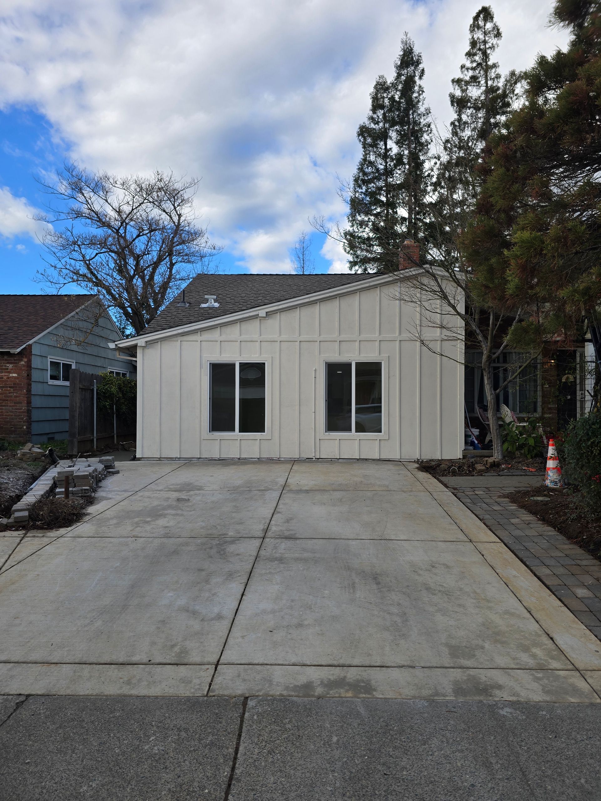 White garage-style building at the end of a concrete driveway under a partly cloudy sky