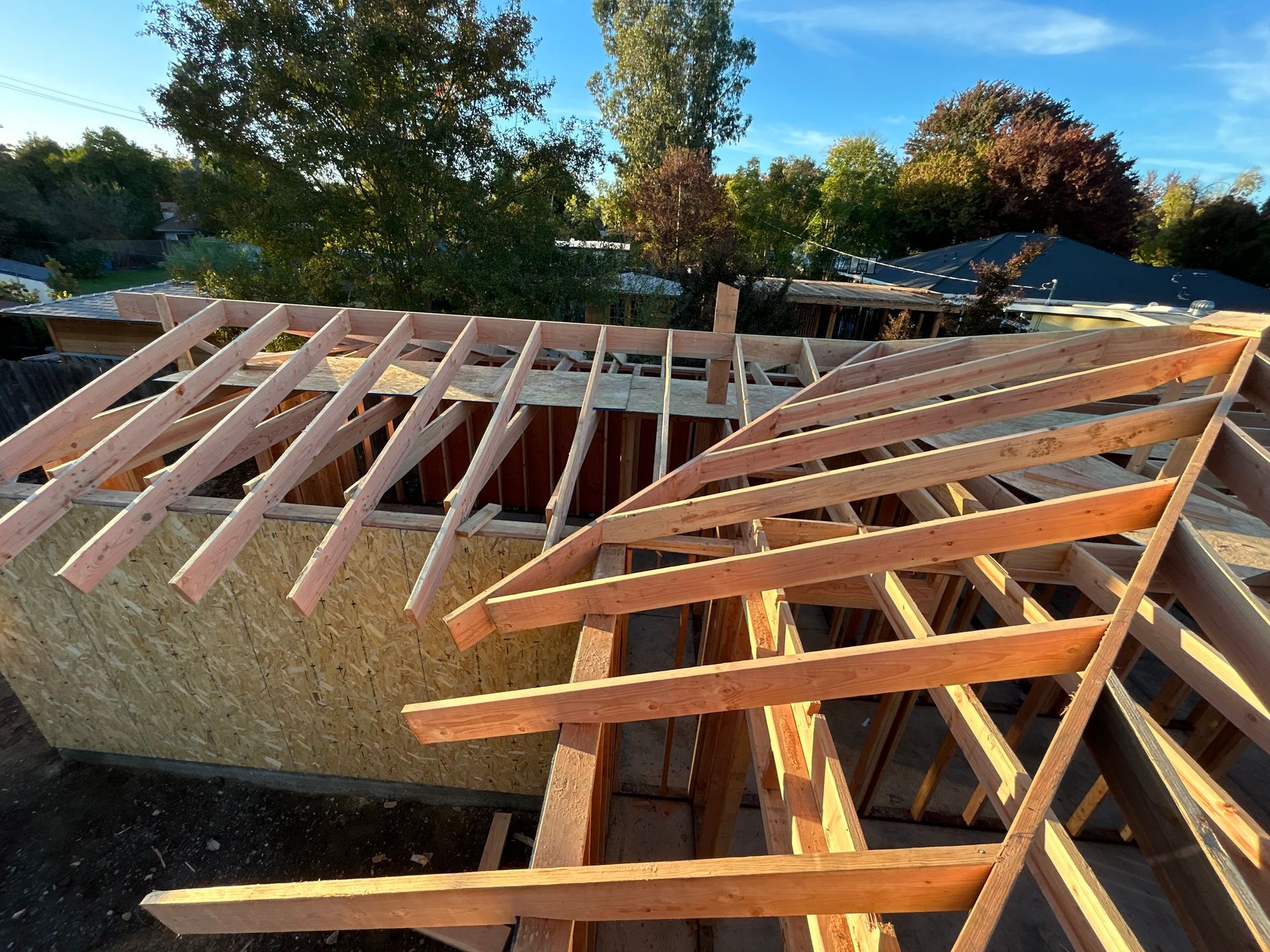 Partially built house roof framing with exposed wooden trusses under construction outdoors