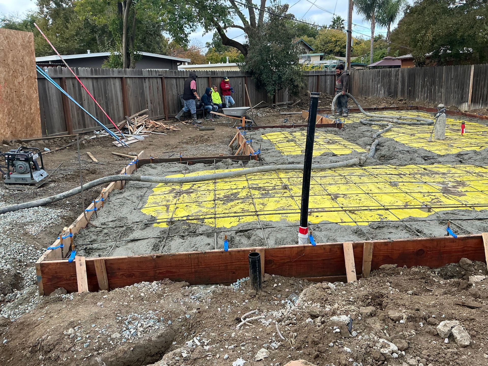 Construction site with rebar foundation and workers in safety vests near wooden forms
