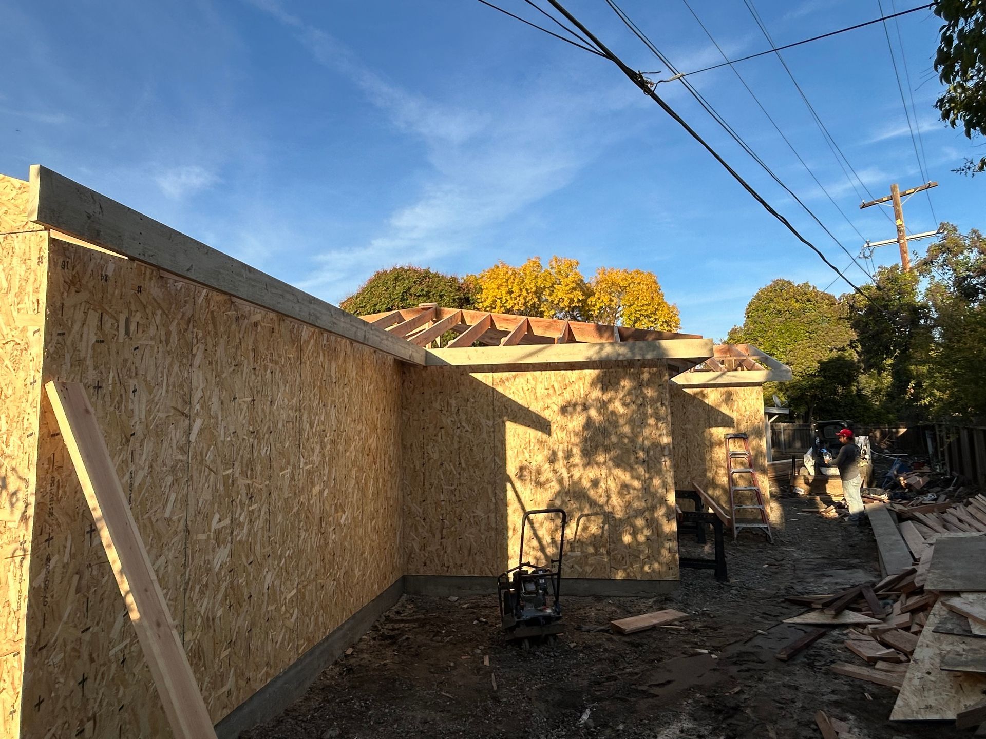Construction site with plywood walls and debris under a blue sky