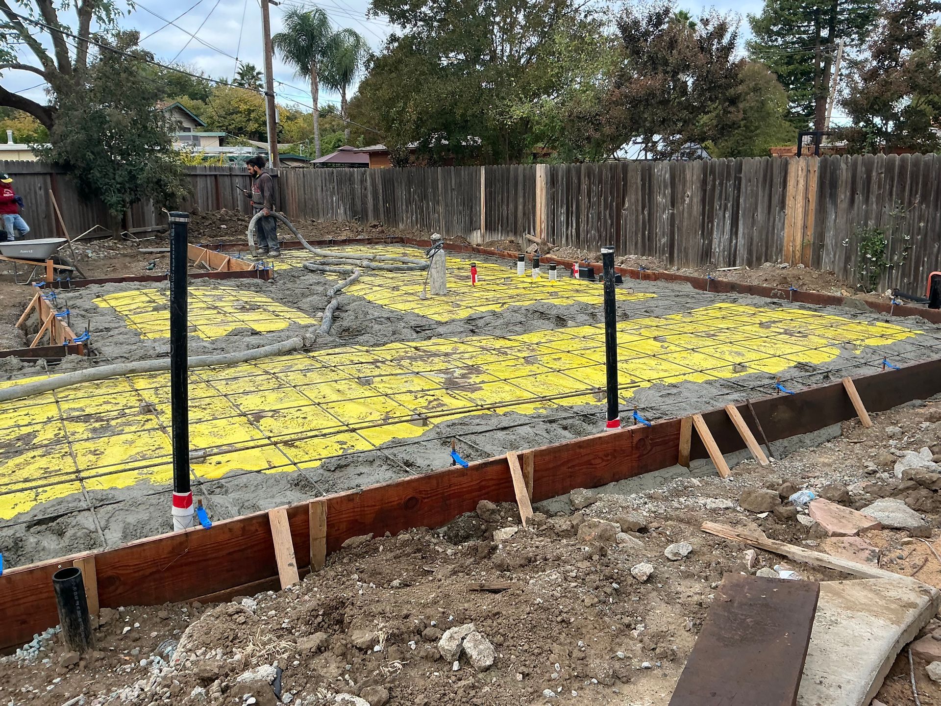 Construction site with rebar grid, yellow vapor barrier, and wooden formwork for a concrete slab