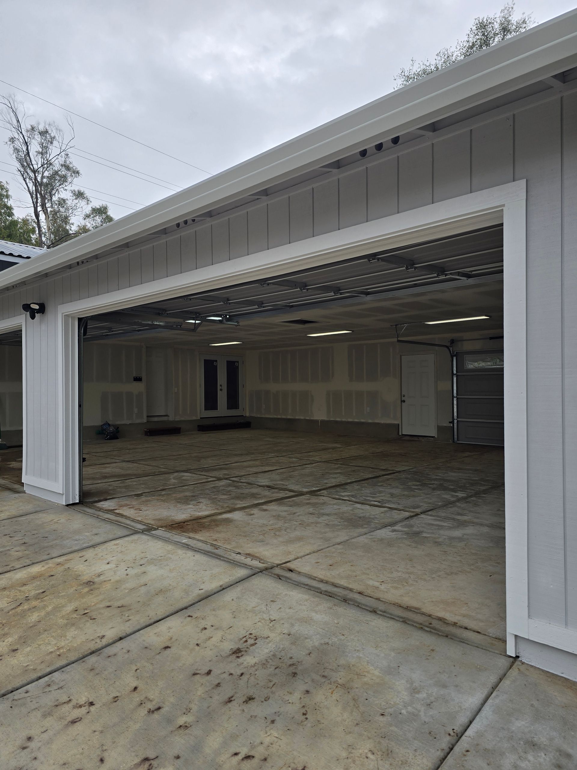 Open garage with white walls and empty concrete floor, viewed from the driveway