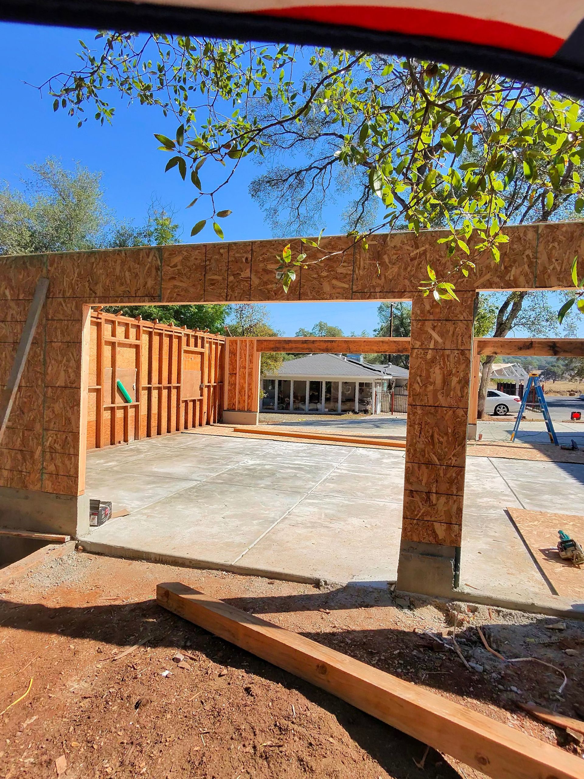 Construction site with unfinished wooden framing and concrete foundation under a clear blue sky