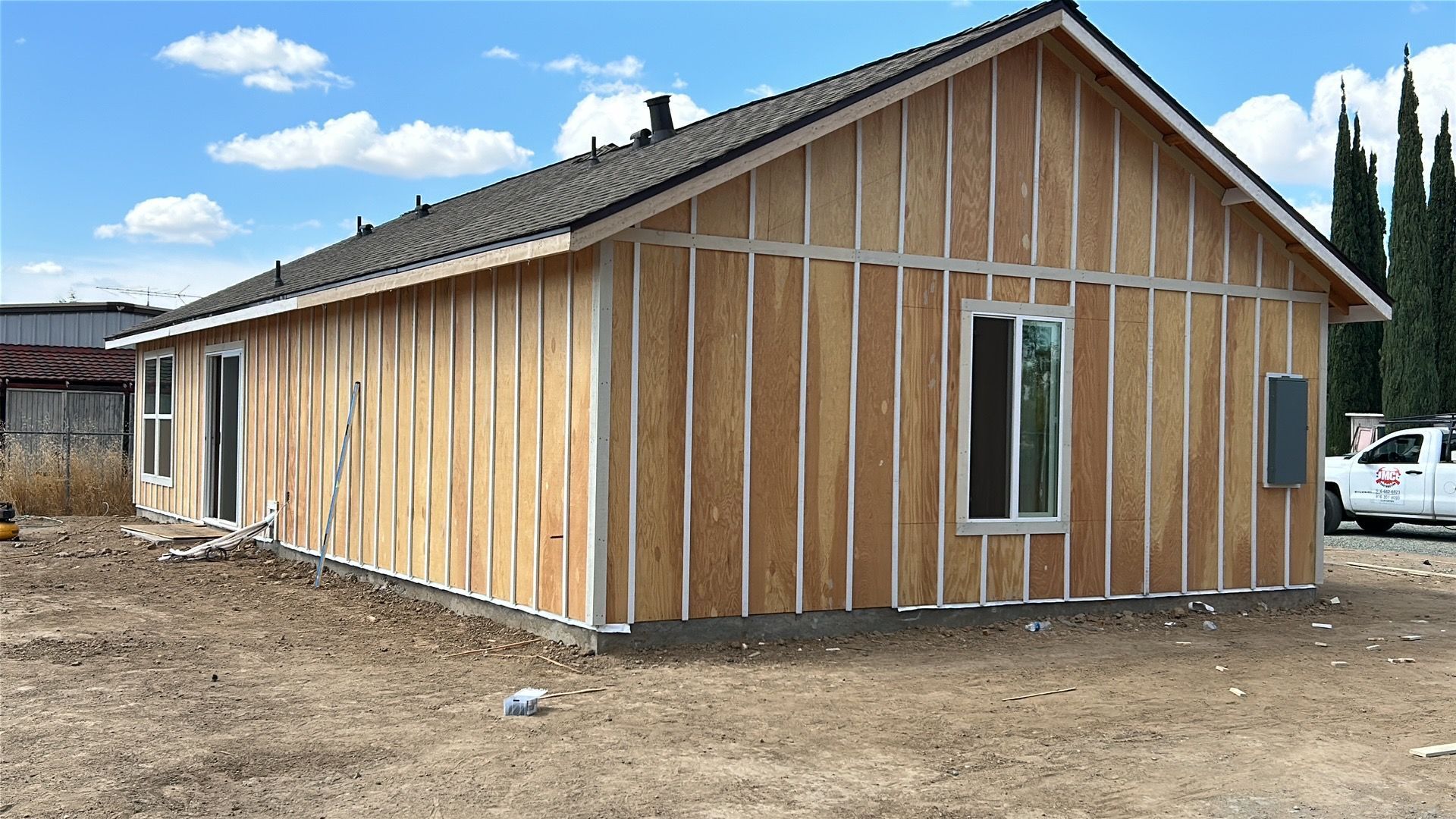 Newly framed wooden house exterior with white trim under a blue sky