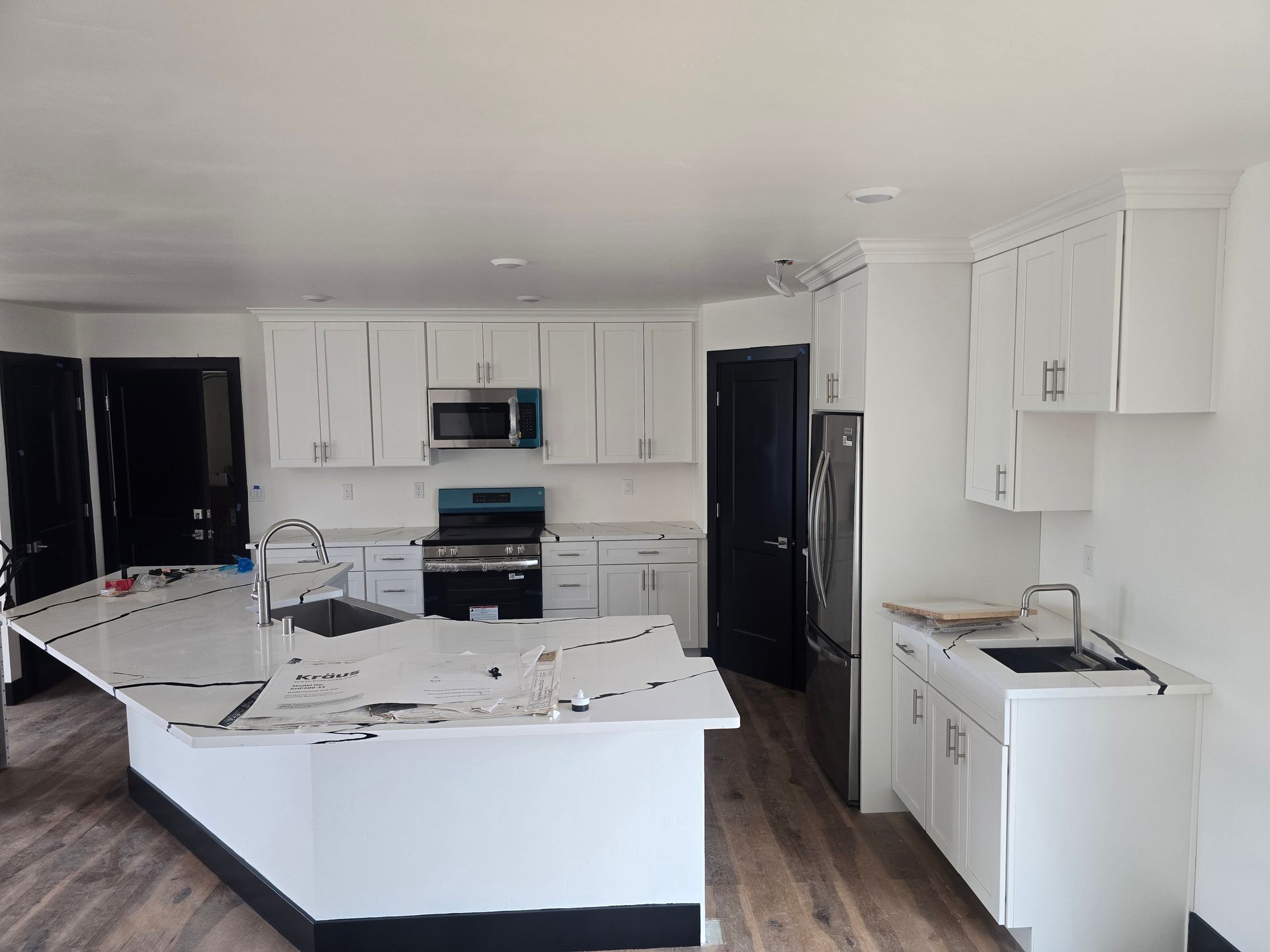 Bright kitchen with white cabinets, black appliances, and a large white island countertop.