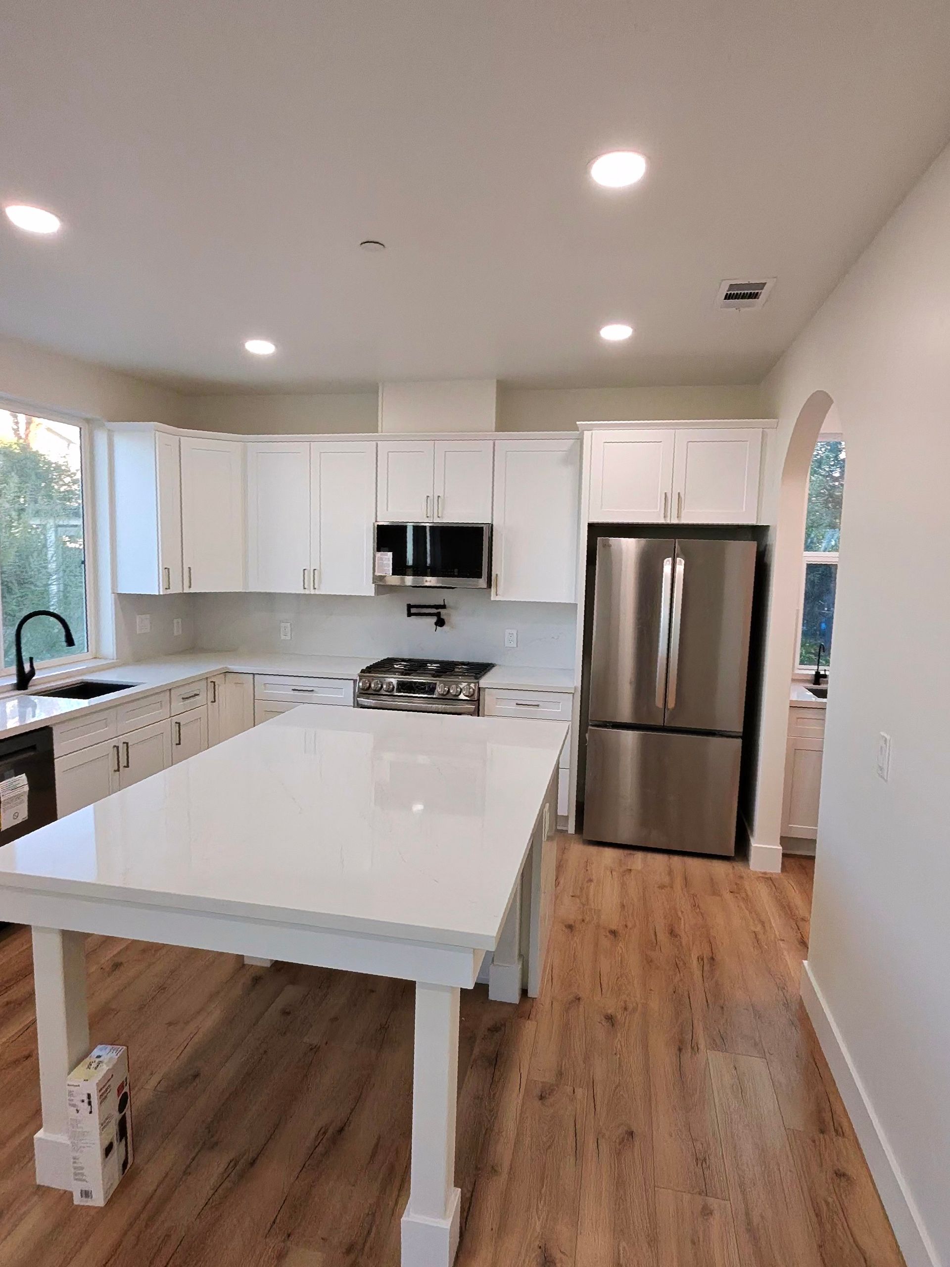 Bright modern kitchen with white cabinets, stainless fridge, and a large island with white countertop.