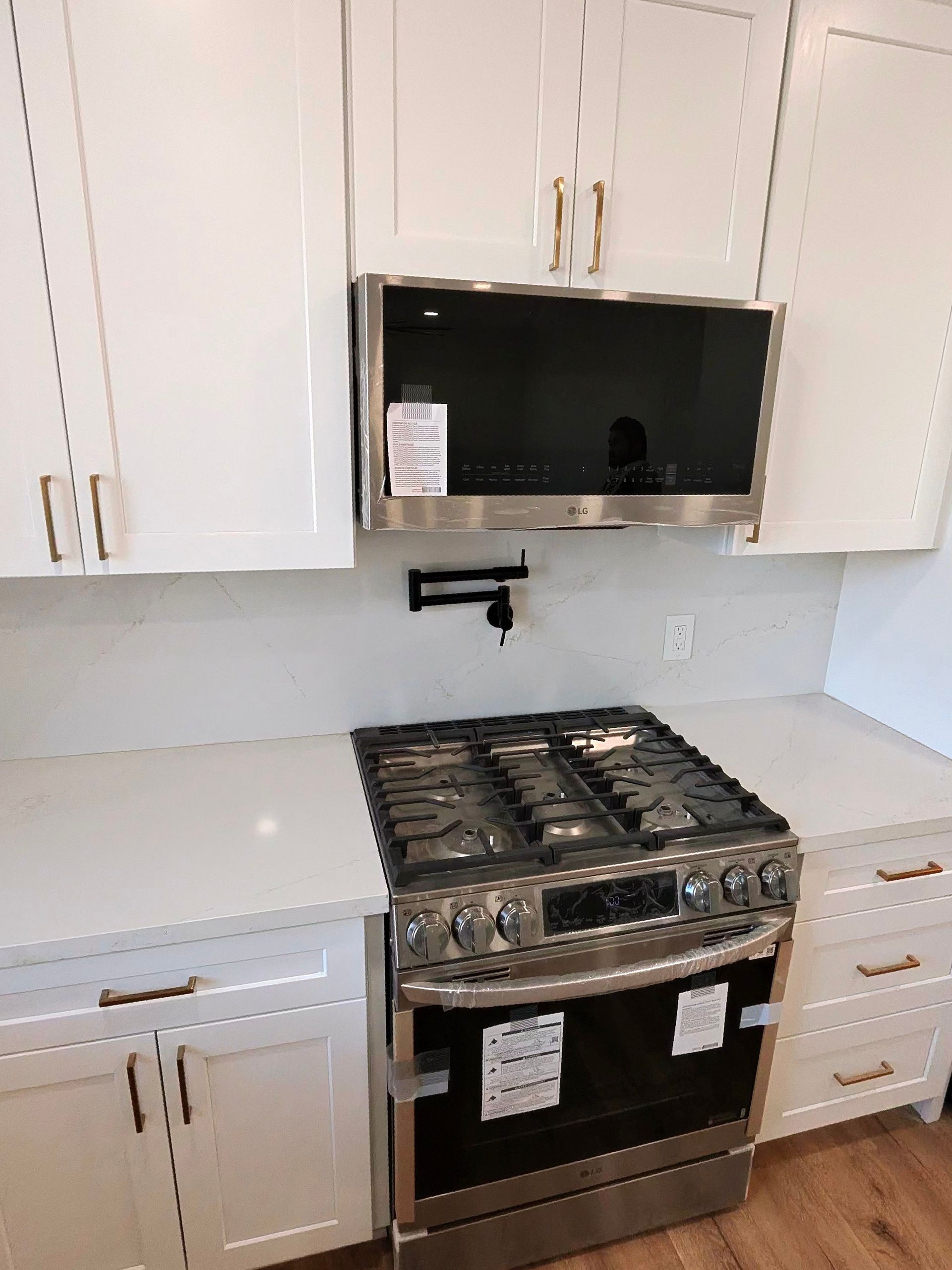 White kitchen with a stainless steel gas range and built-in microwave under white cabinets.