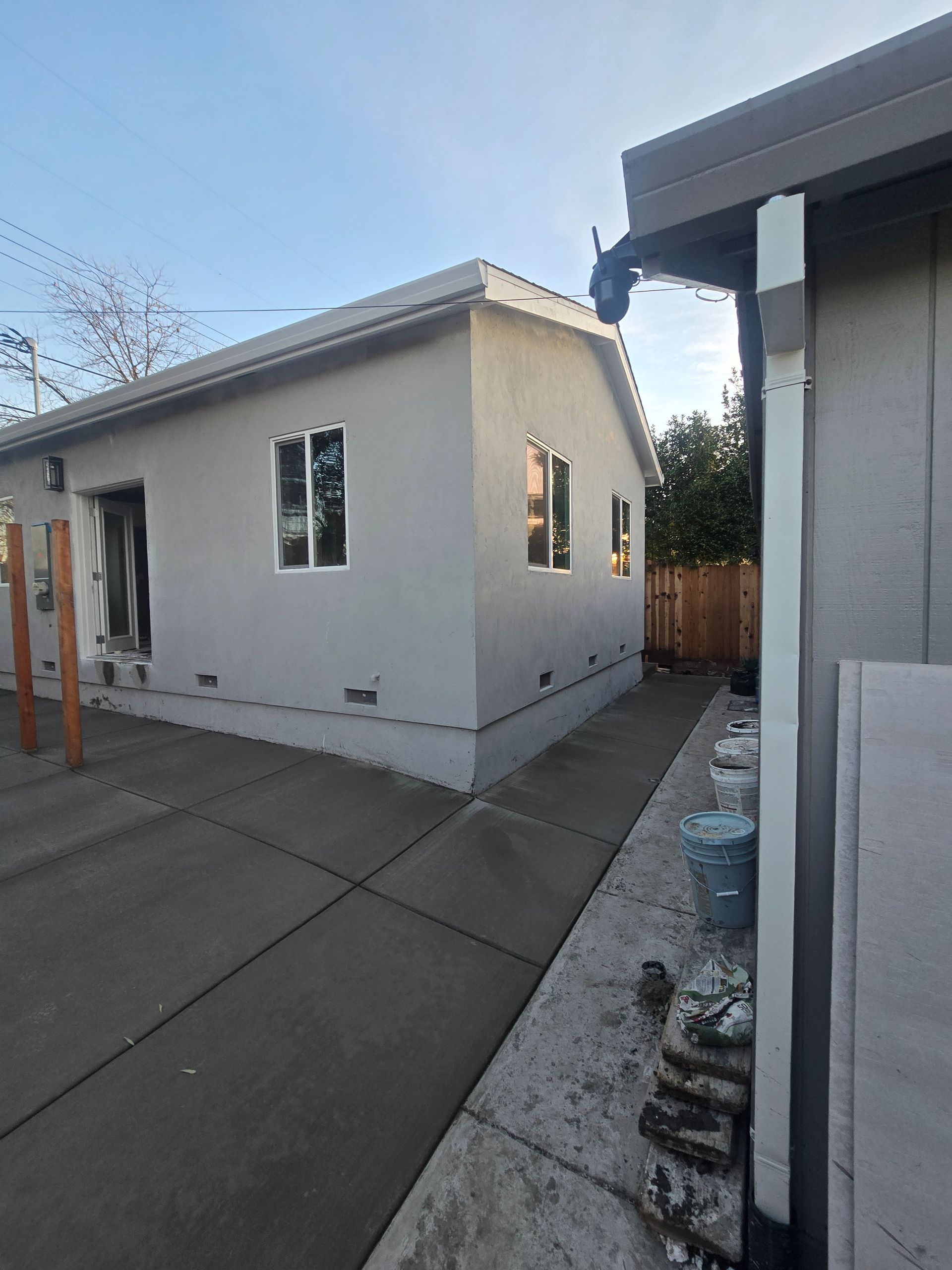Backyard with a small white shed, concrete patio, and neighboring house wall at dusk