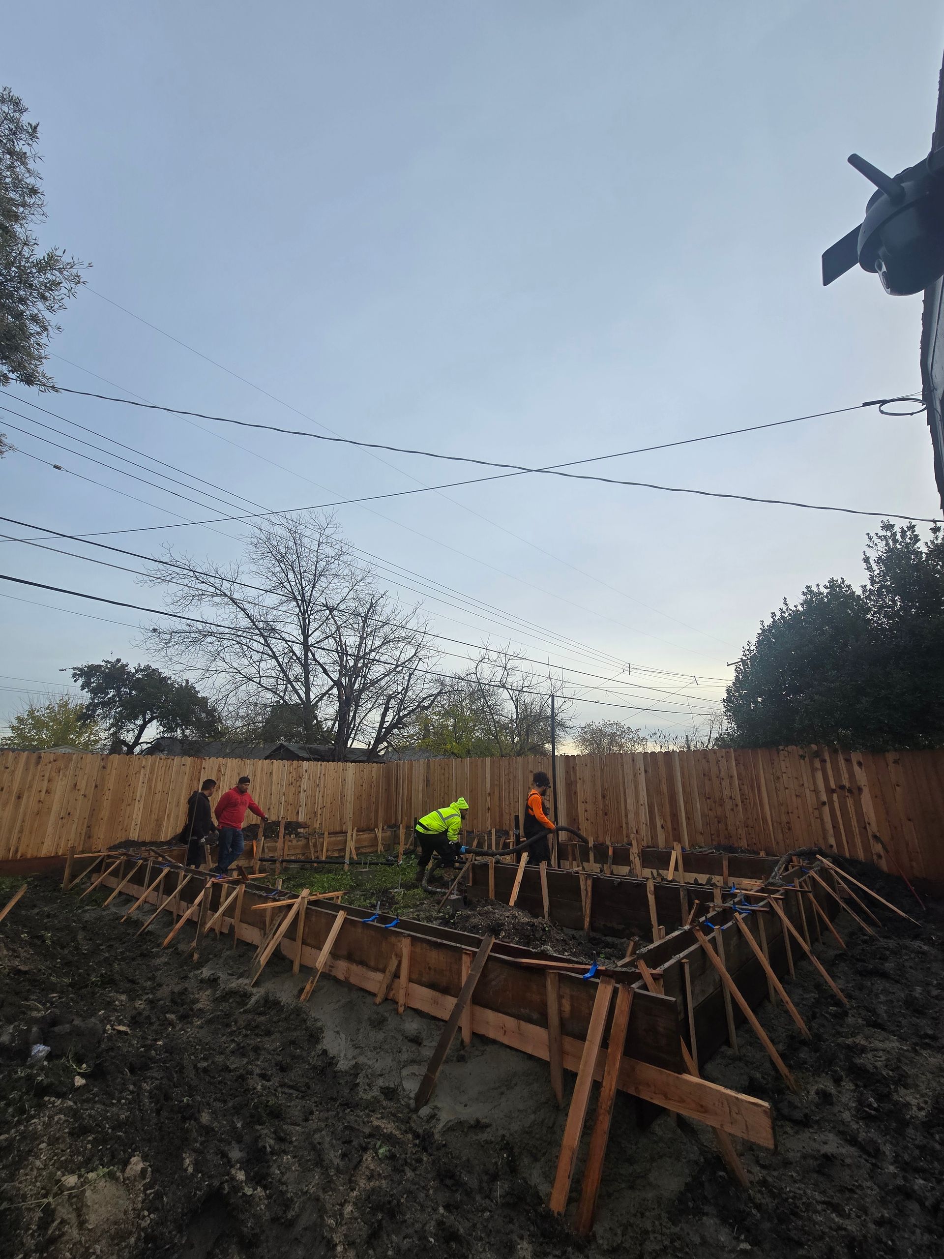 Workers building wooden formwork for a concrete structure outdoors at dusk
