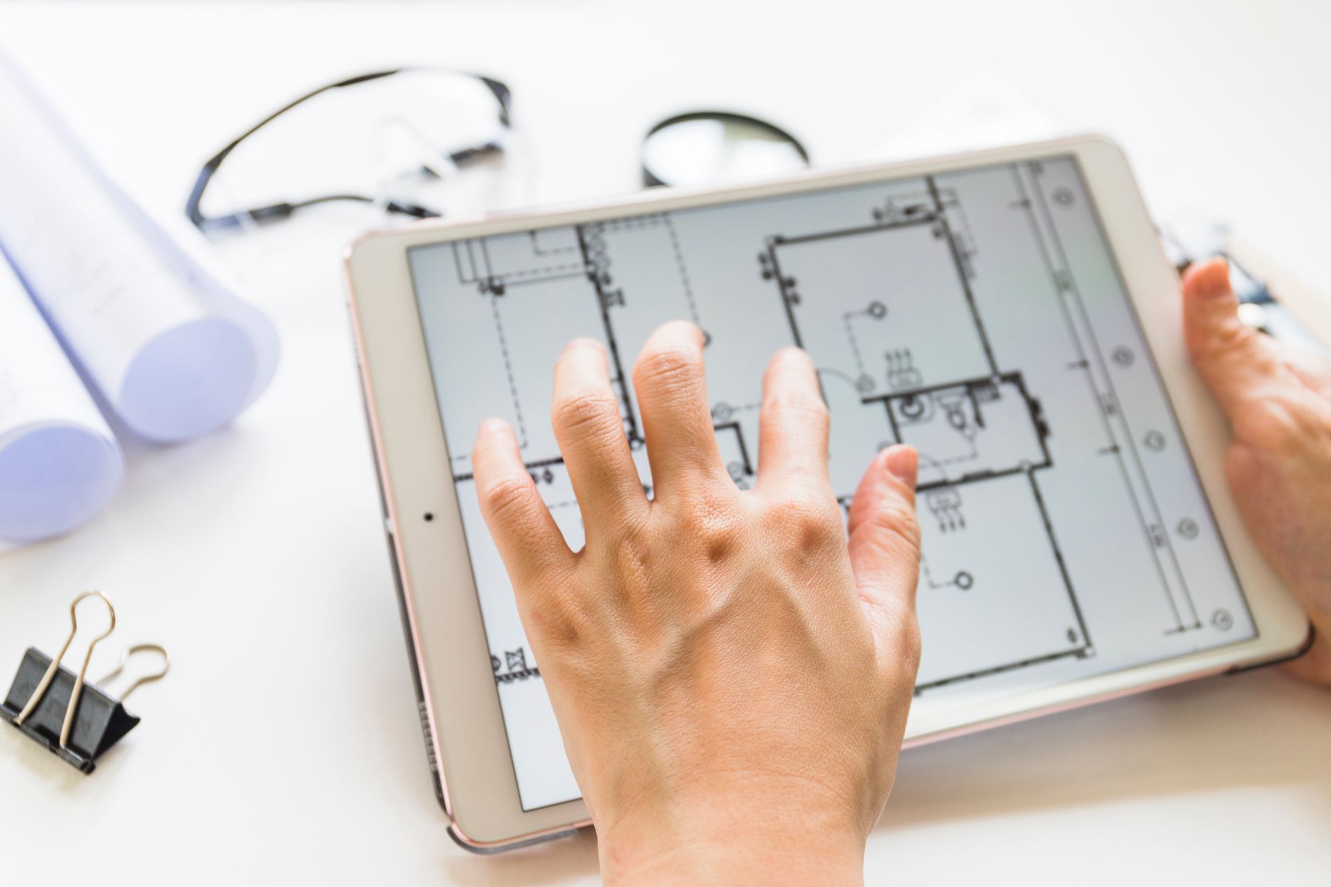 Hands using a tablet to view a floor plan on a desk