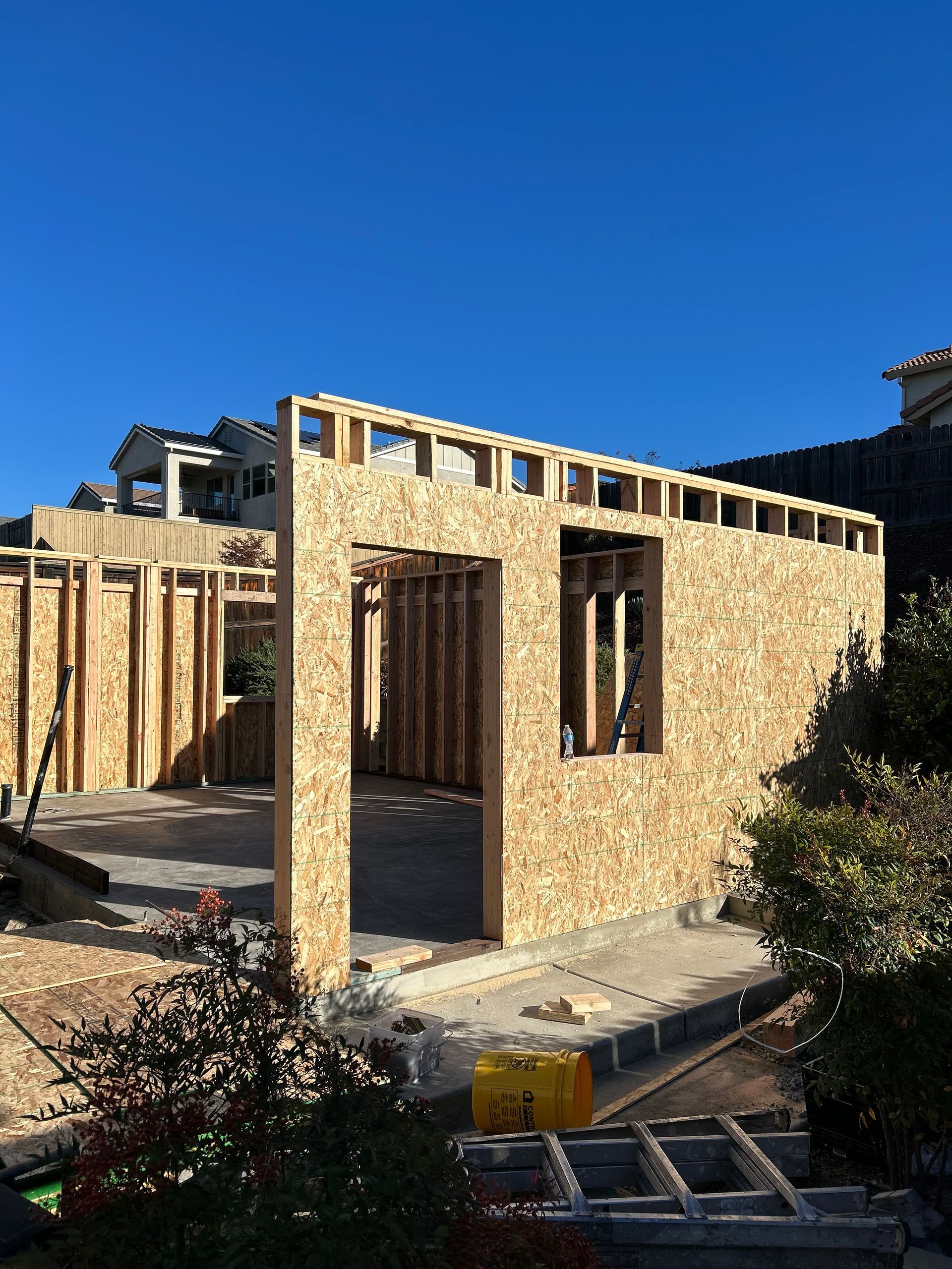 Partially built wooden house frame under construction in bright sunlight