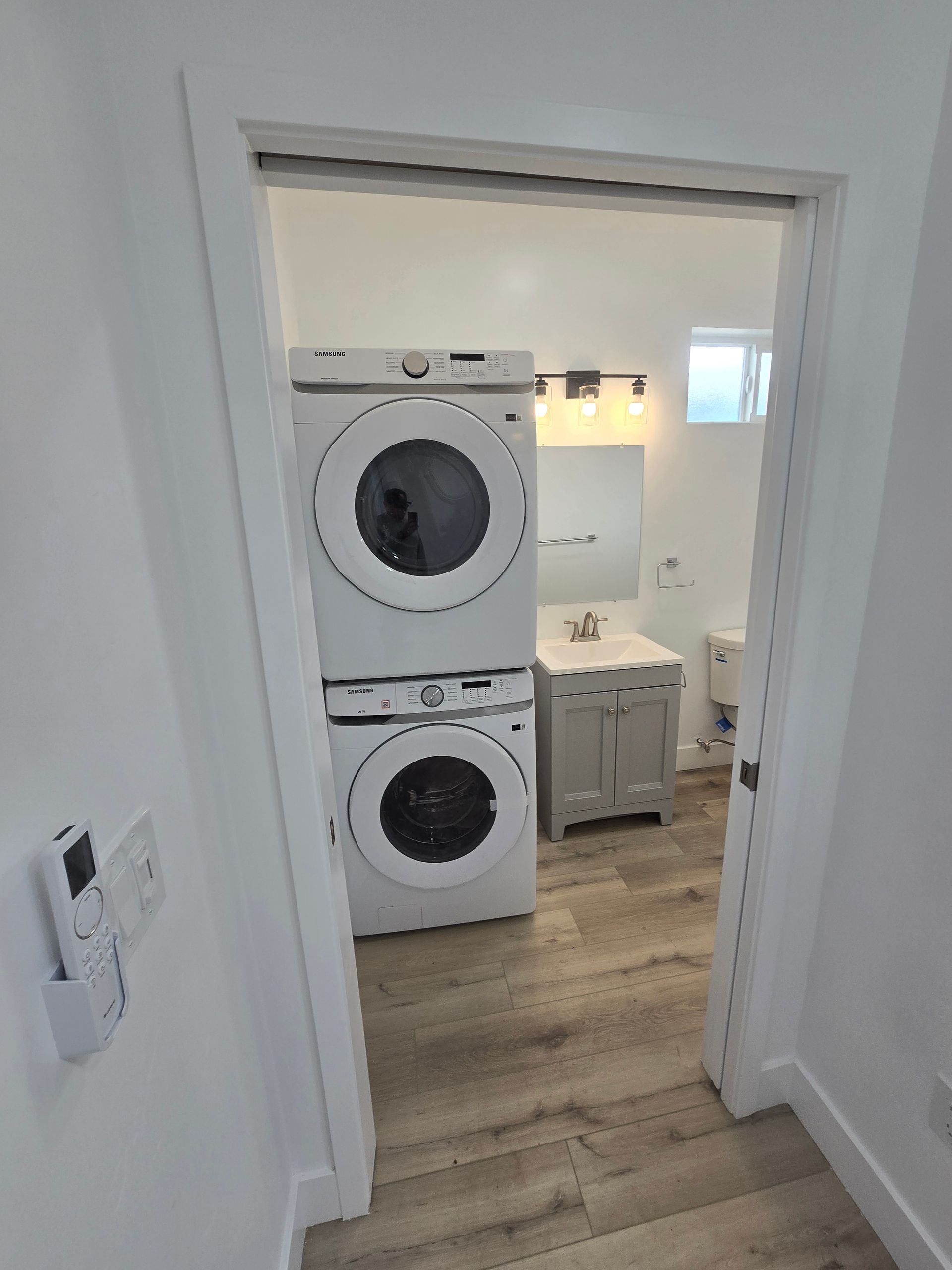 Stacked washer and dryer in a laundry room, viewed through a doorway.