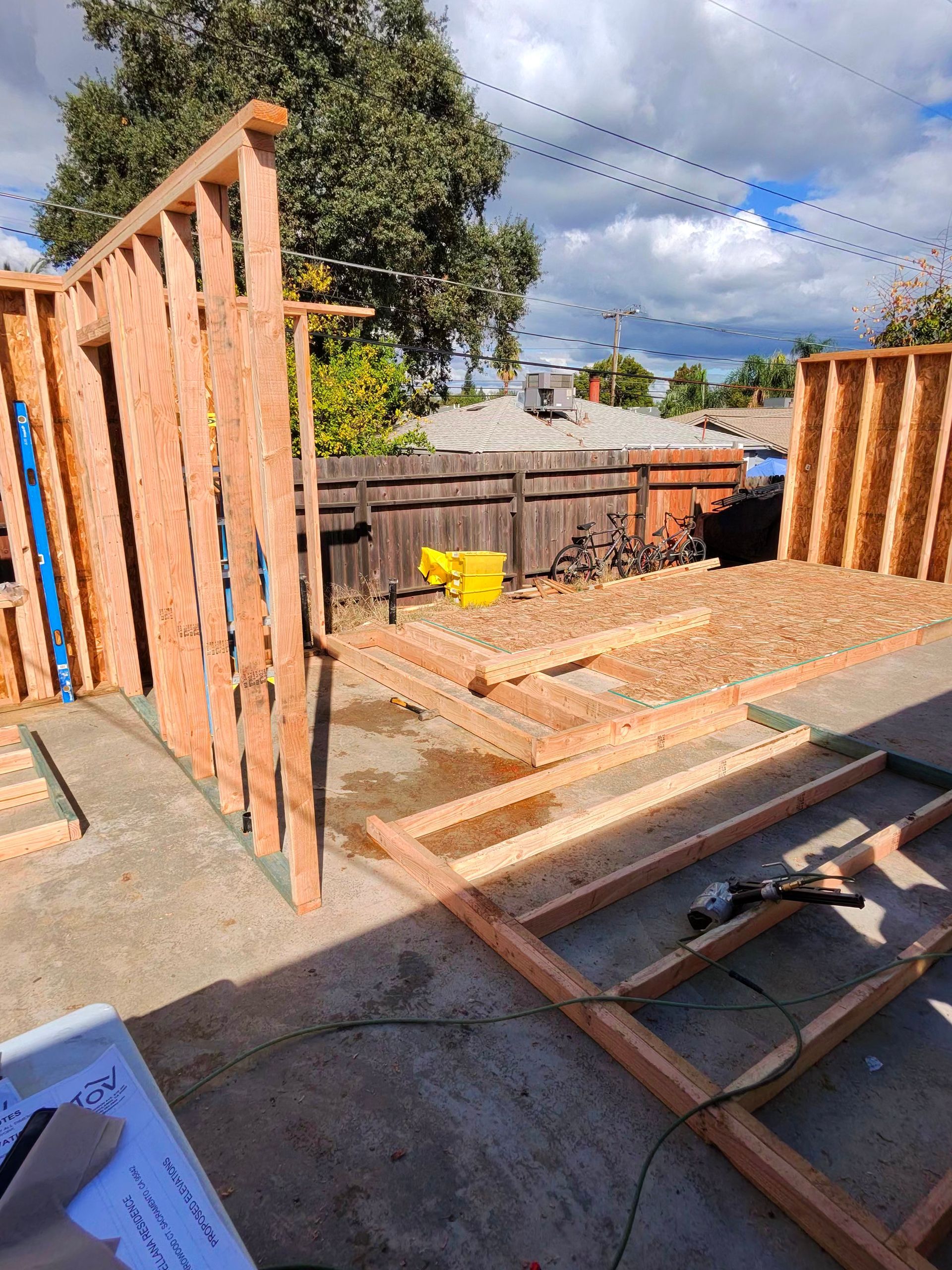 Construction site with wooden framing and open deck under a partly cloudy sky