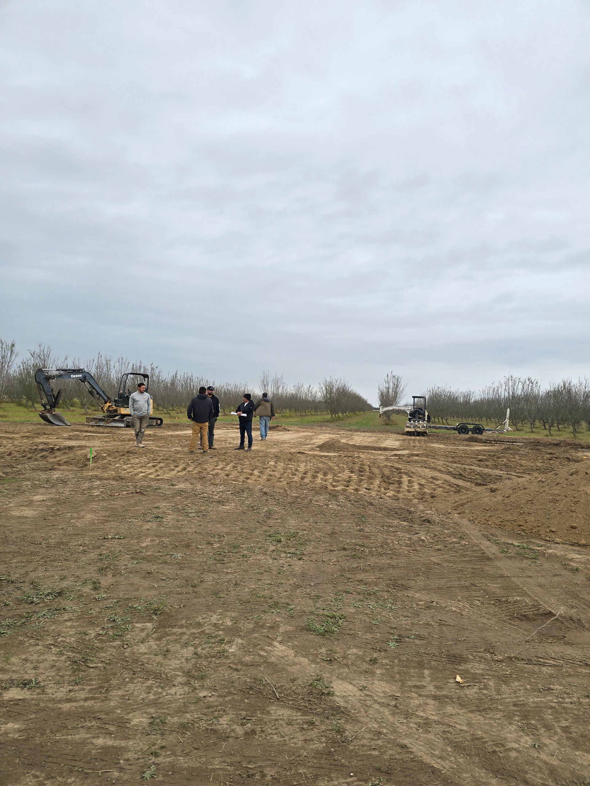 People walking across a barren field under a cloudy sky.