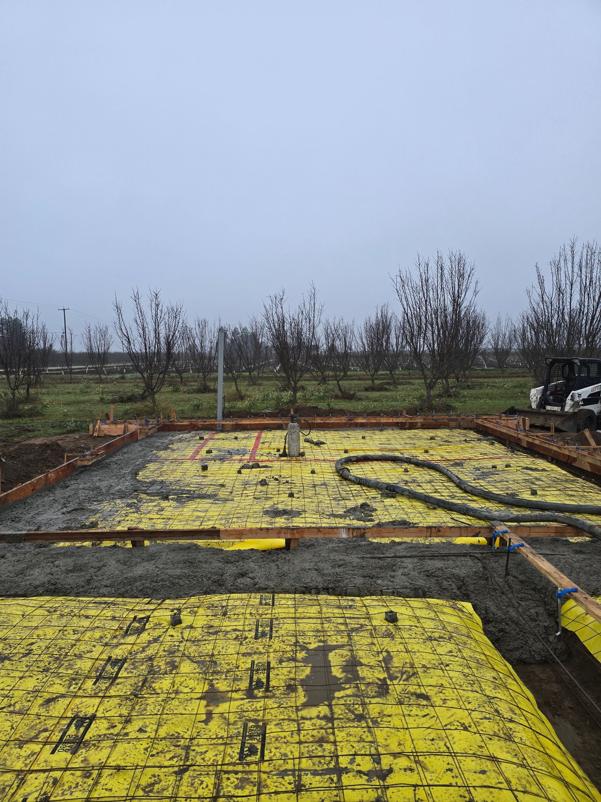 Yellow insulation boards laid out on the ground at a construction site under an overcast sky
