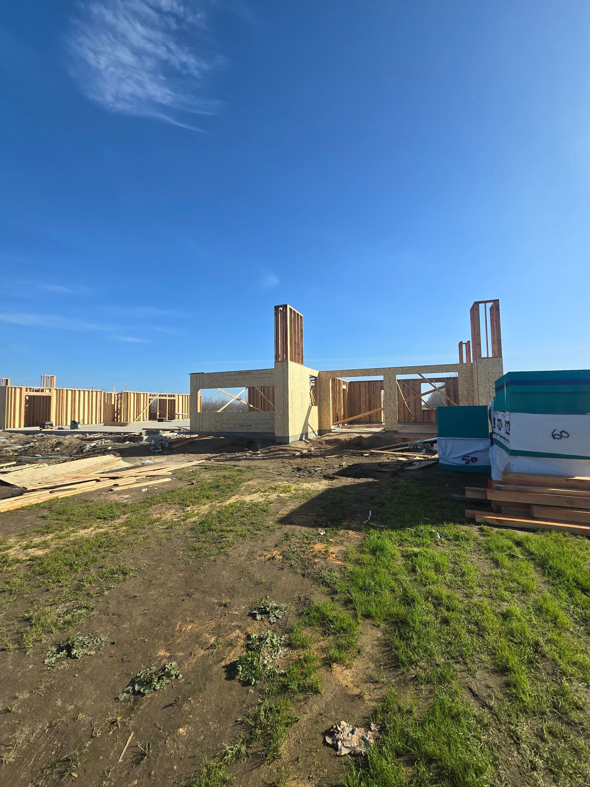 Ruins of a burned-out building under a clear blue sky, with dirt and grass in the foreground.