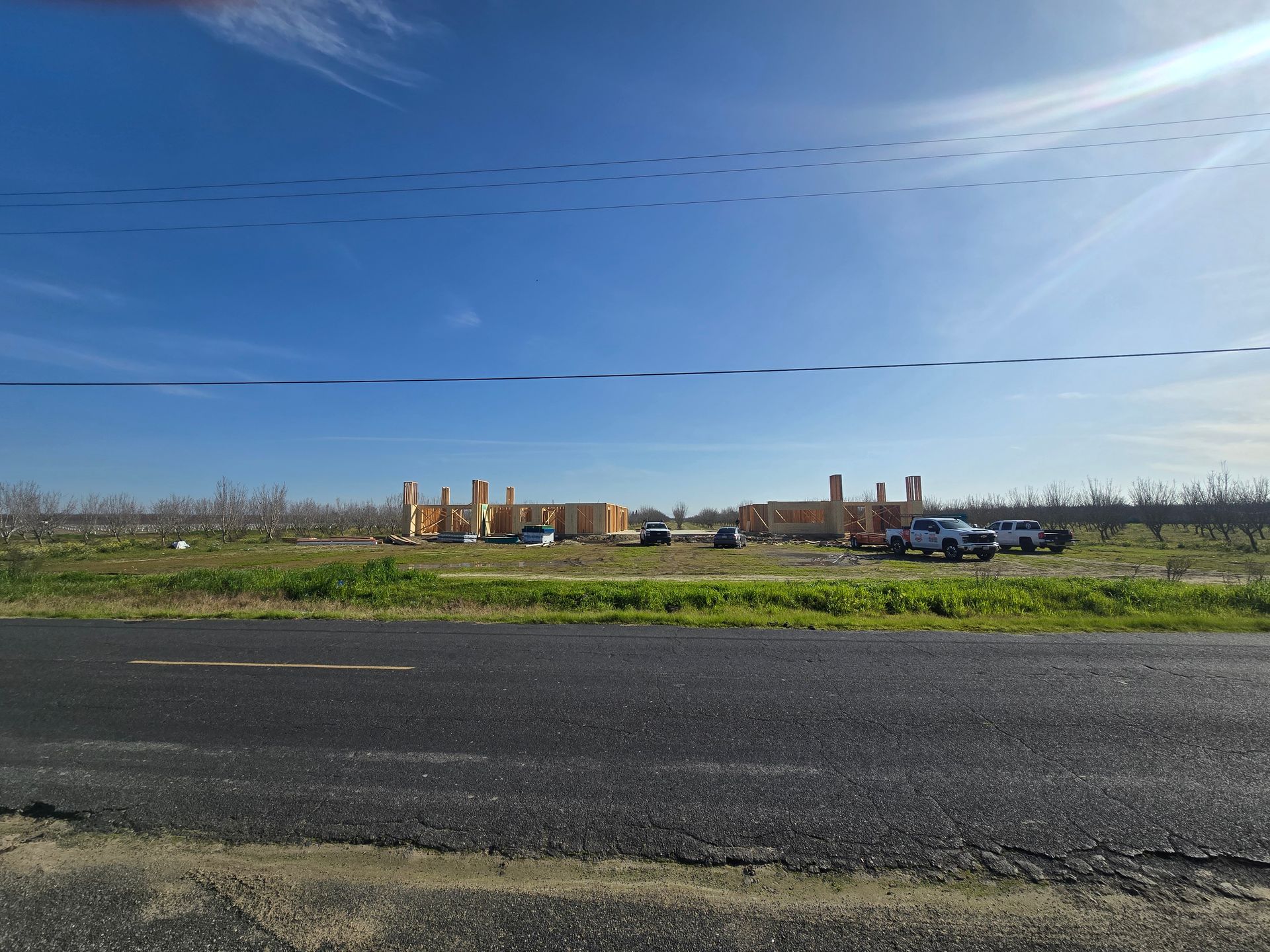 Damaged roadside with parked cars and collapsed brick buildings under a clear blue sky