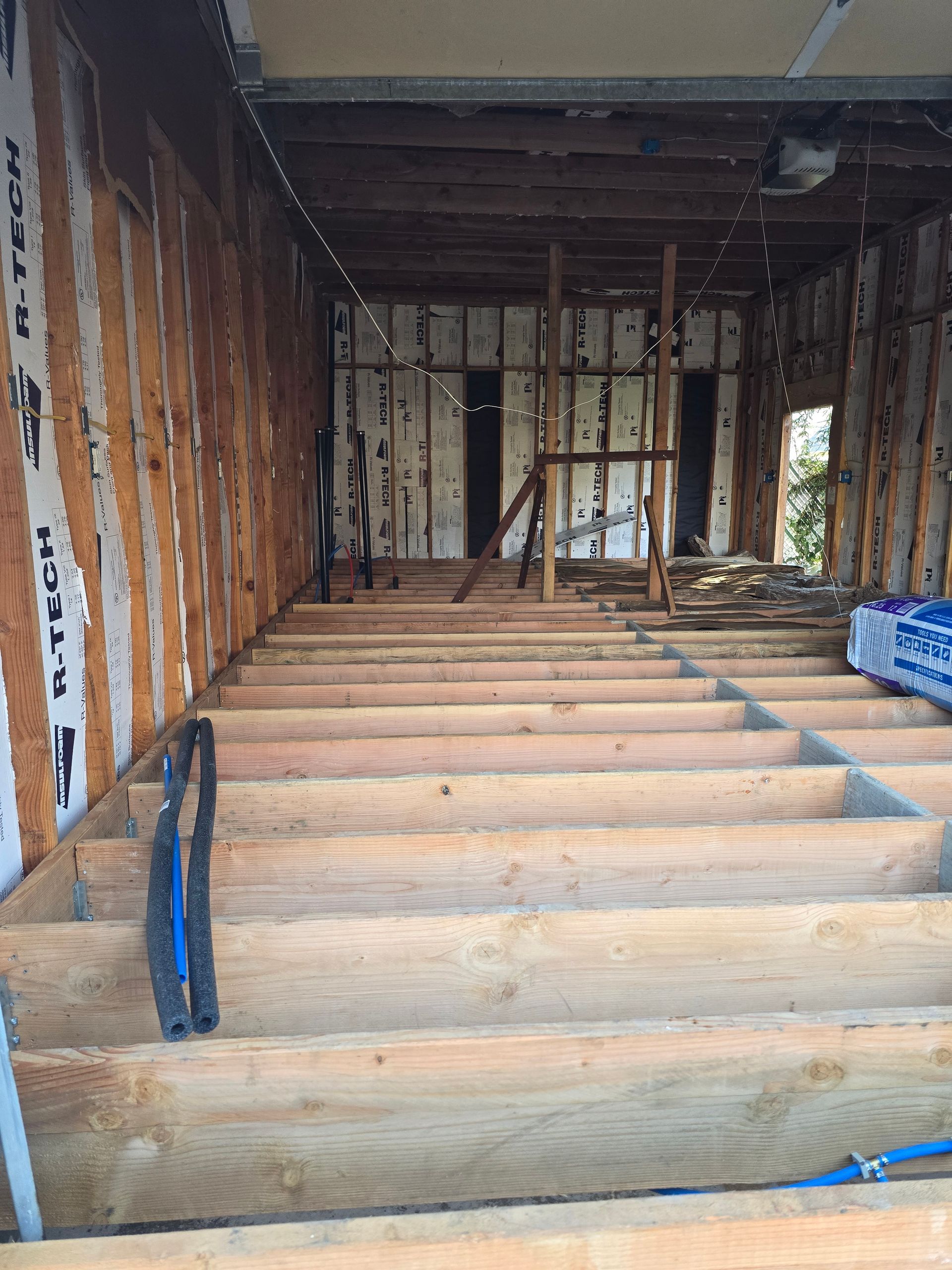 Unfinished interior with exposed wooden framing and floor joists in a construction site