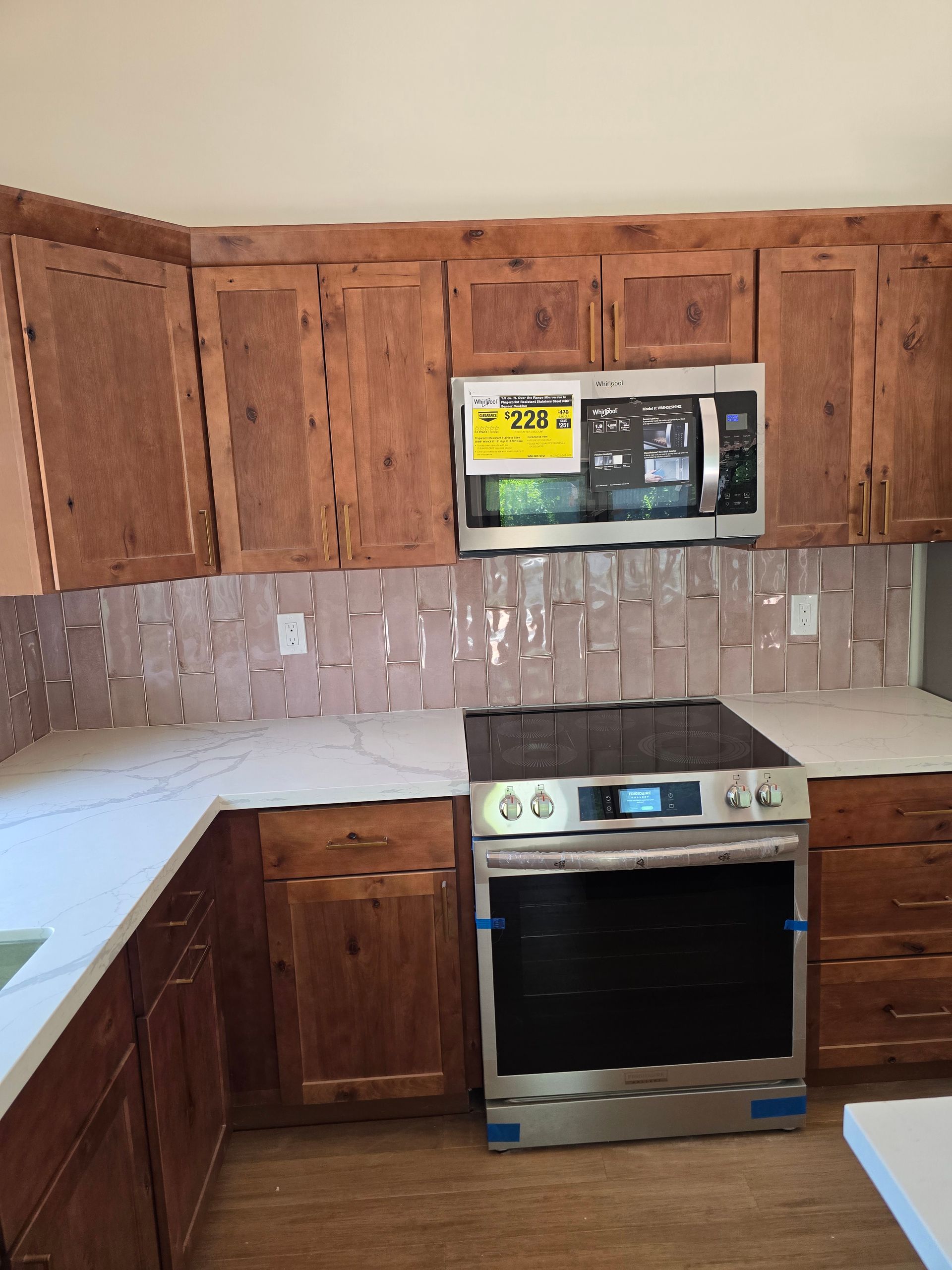 Small kitchen with wooden cabinets, beige tile backsplash, white countertops, and a stainless steel stove.