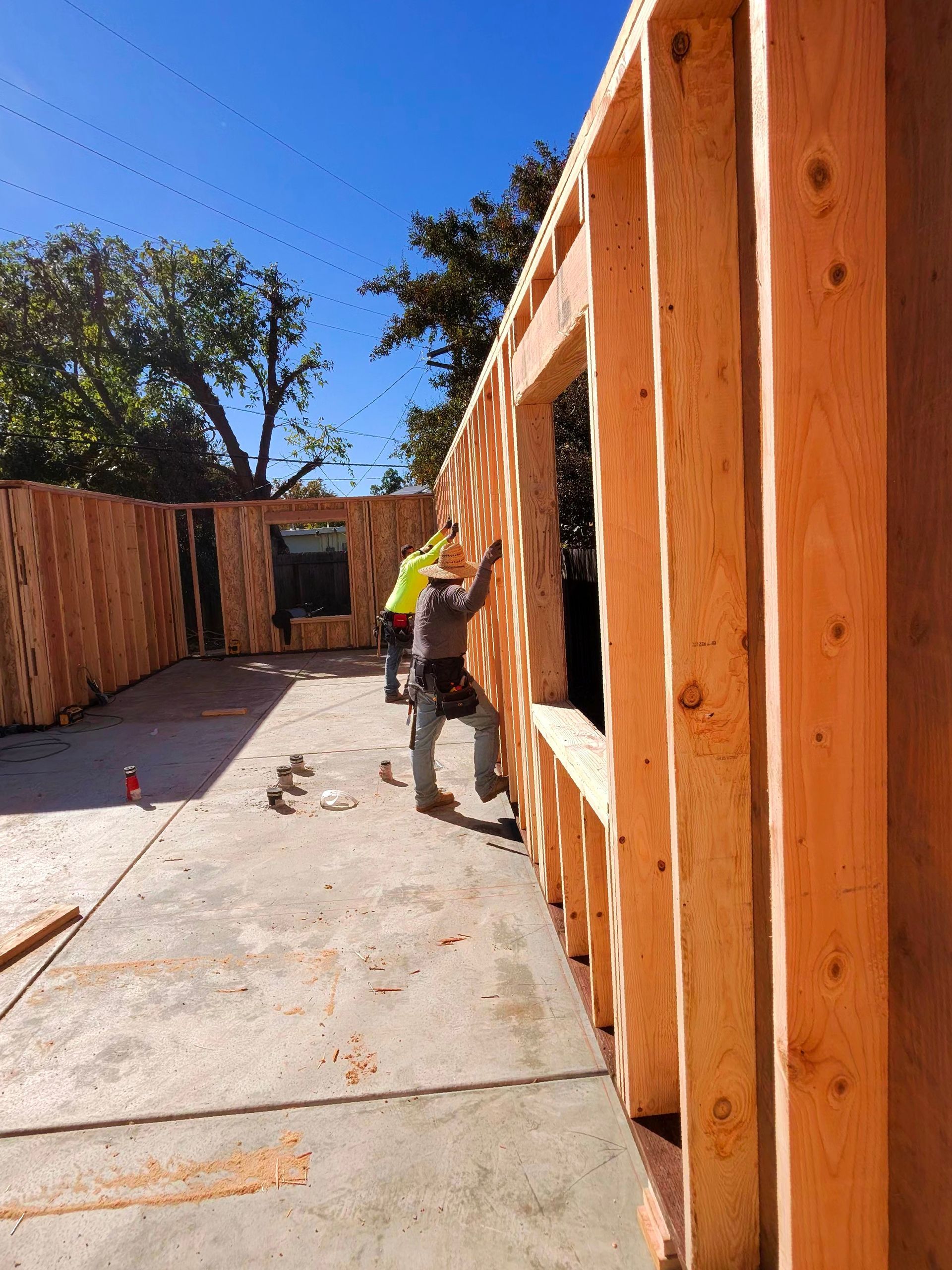 Partially built small house with plywood walls, rust-colored roof, and construction materials around it