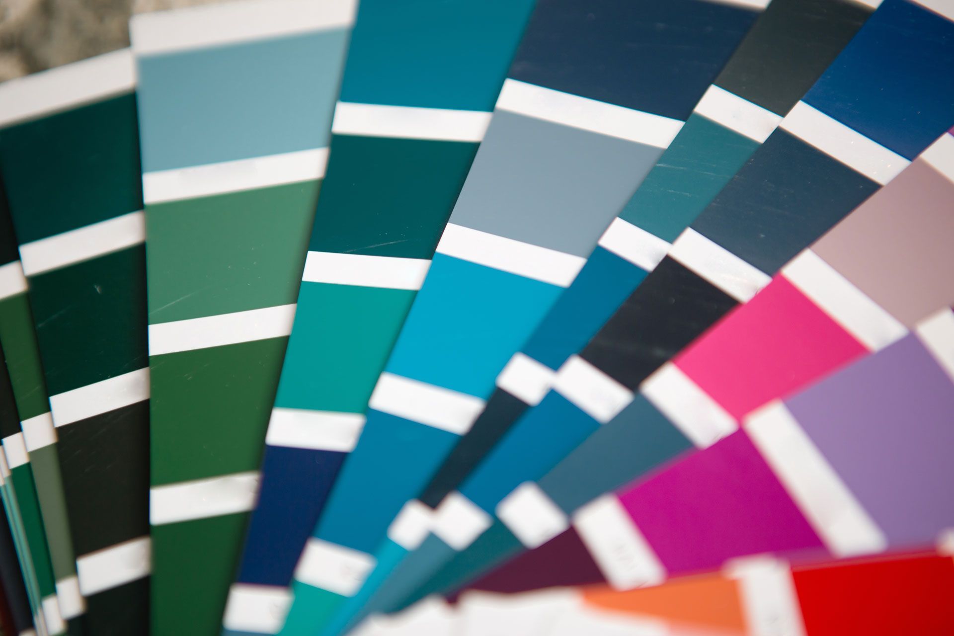 Fan of colorful fabric swatches in teal, blue, pink, purple, and red on a white background