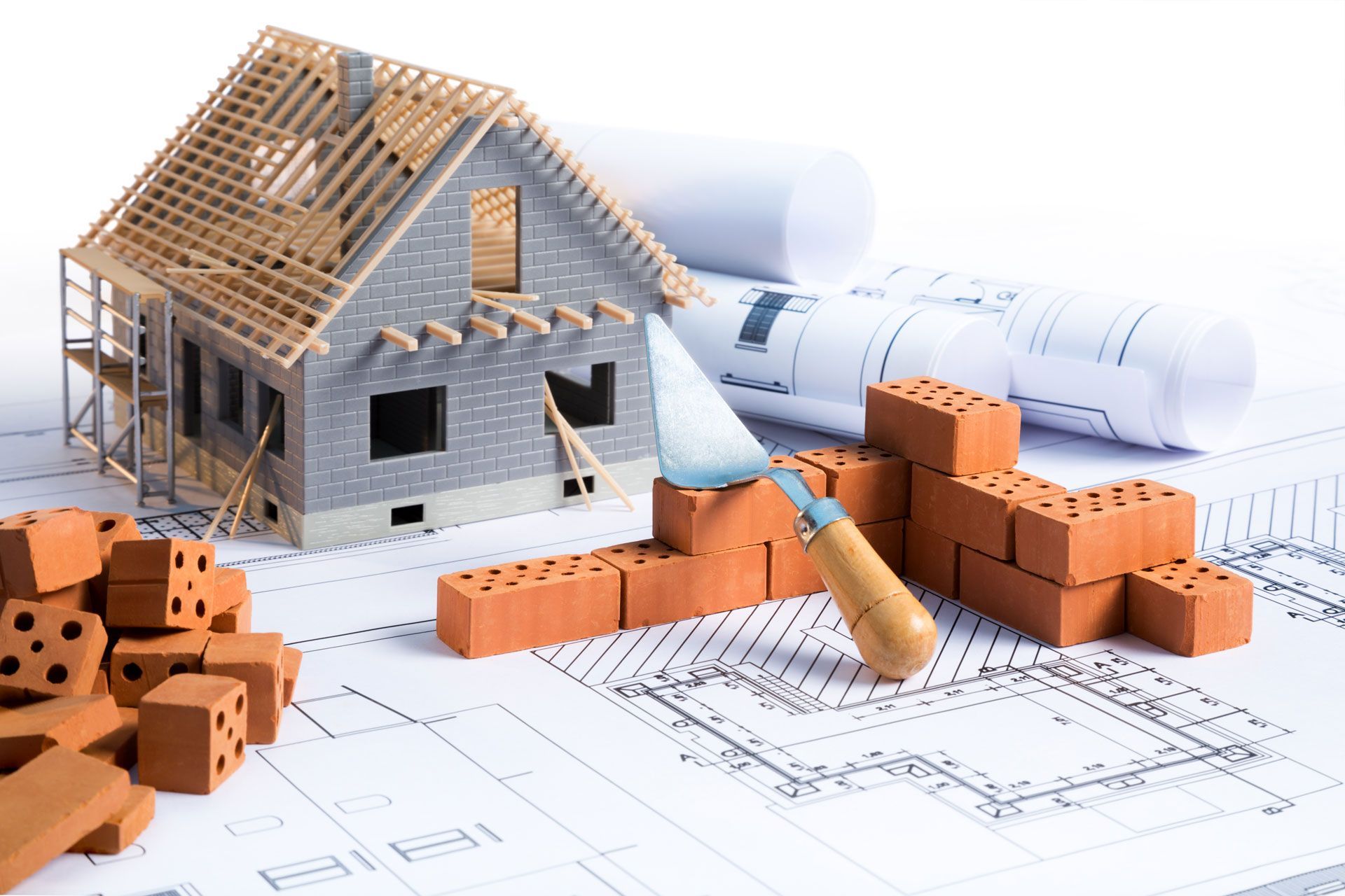 3D house model with blueprints, pencil, and scattered orange bricks on a construction plan