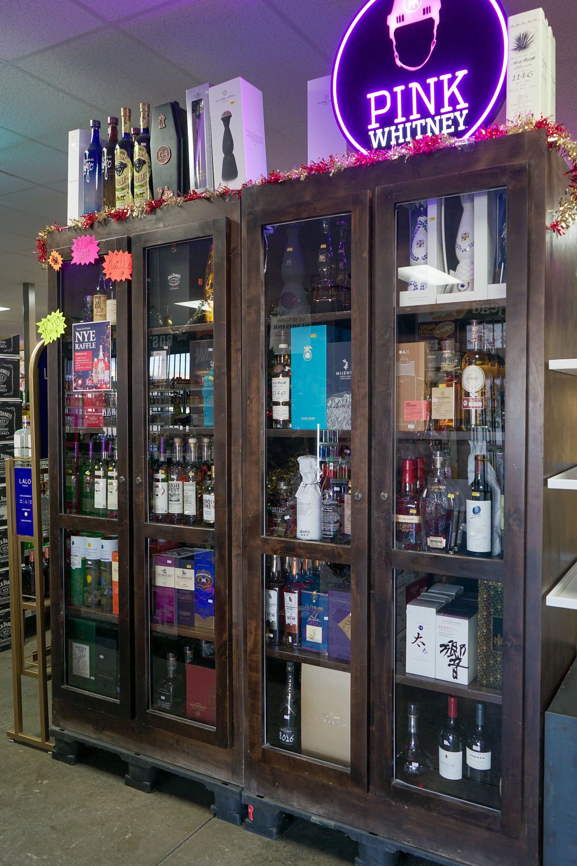 Wooden display cabinet filled with liquor bottles, lit by a