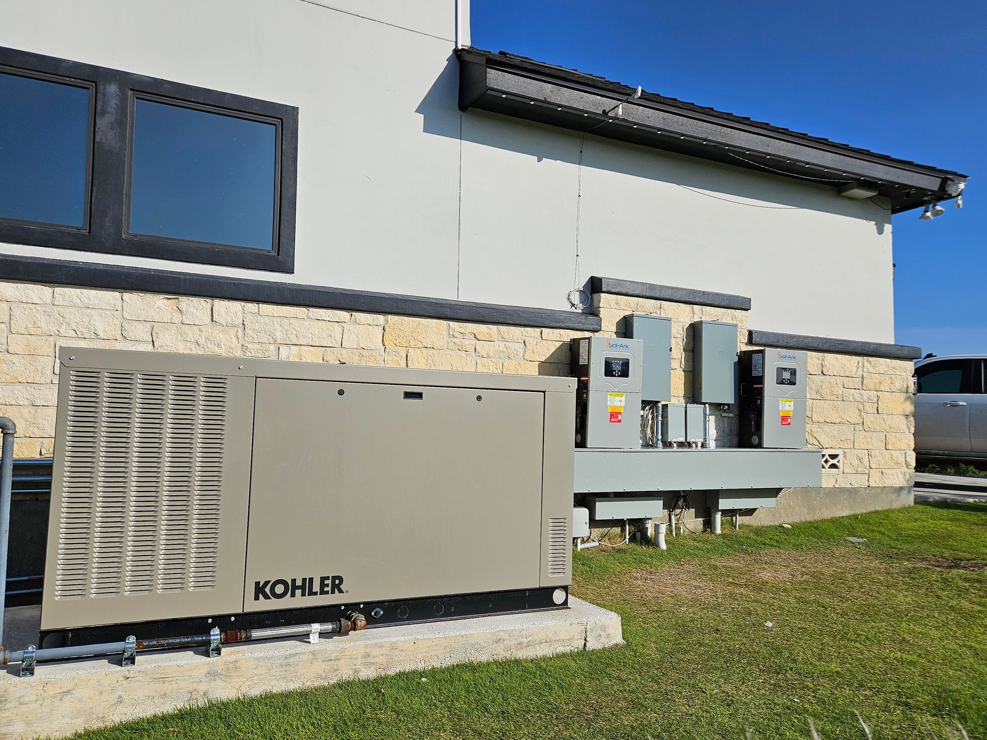 Two outdoor KOHLER generators beside a building, one beige and one gray.