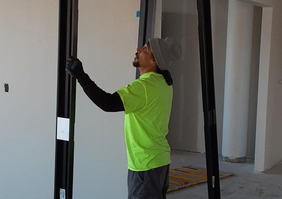 Worker in neon green shirt installing a sliding door frame inside a construction site