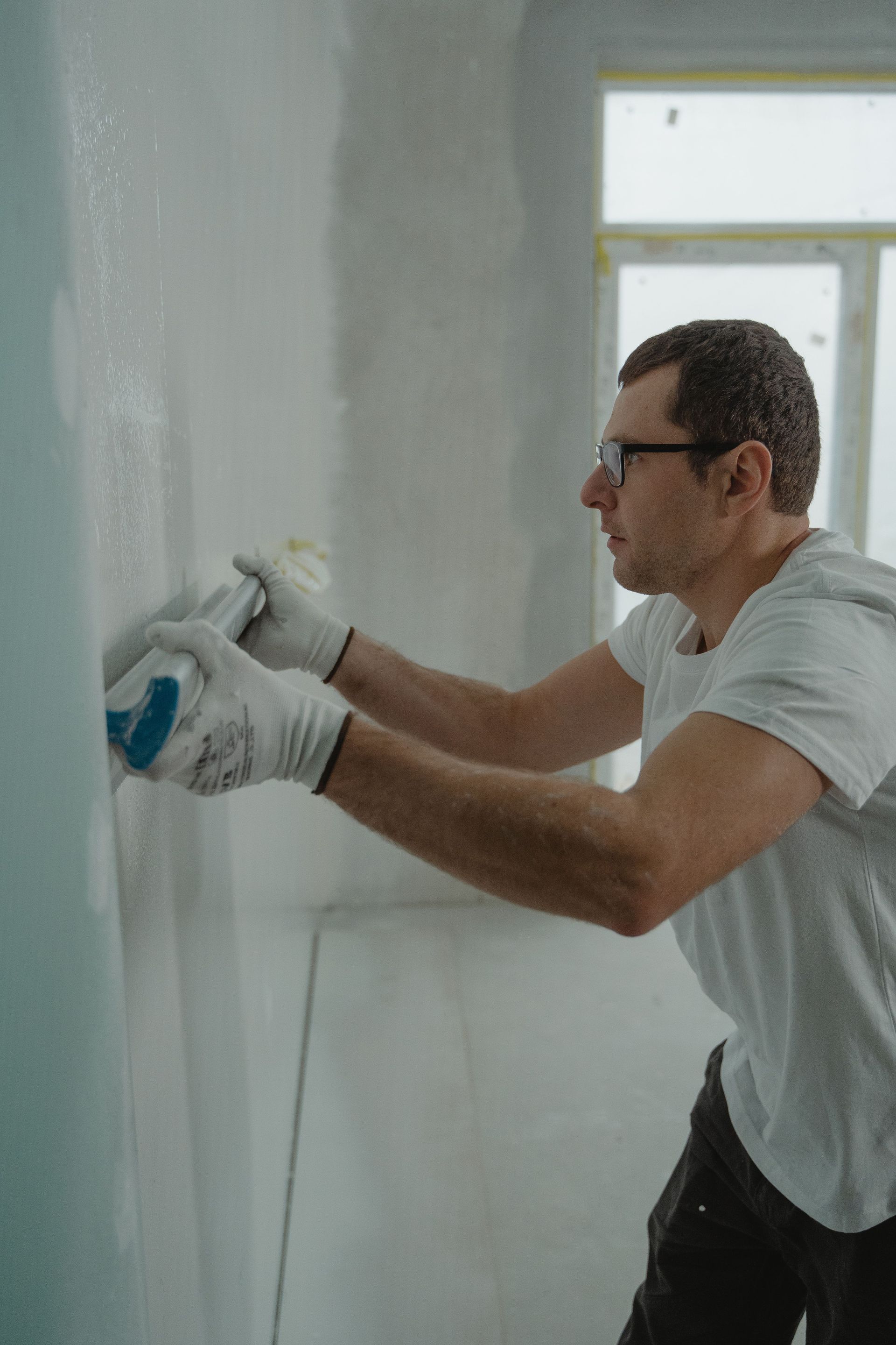 Person cleaning a bright office, wiping a white table with yellow gloves and supplies nearby