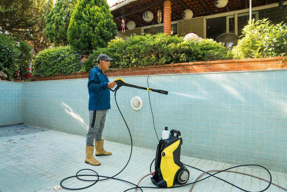 A Man is Using a High Pressure Washer to Clean a Swimming Pool — Lismore Poolscene in Lismore, NSW