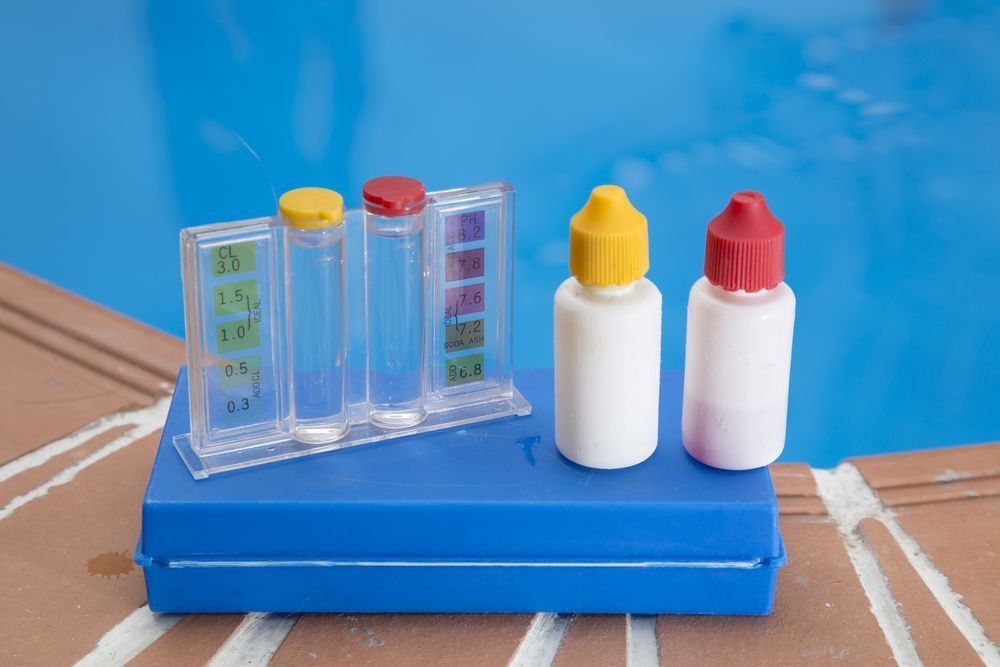 Three Bottles of Chemicals Are Sitting on Top of a Blue Box Next to a Swimming Pool — Lismore Poolscene in Lismore, NSW