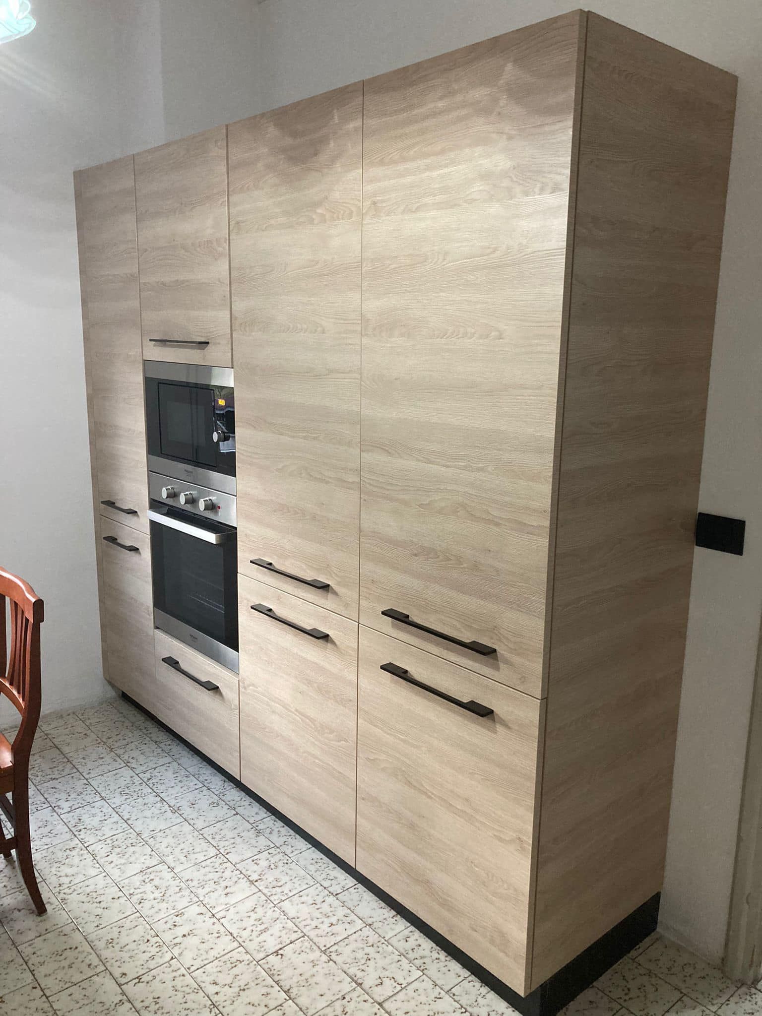 Una cucina con mobili in legno e forno in acciaio inox.
