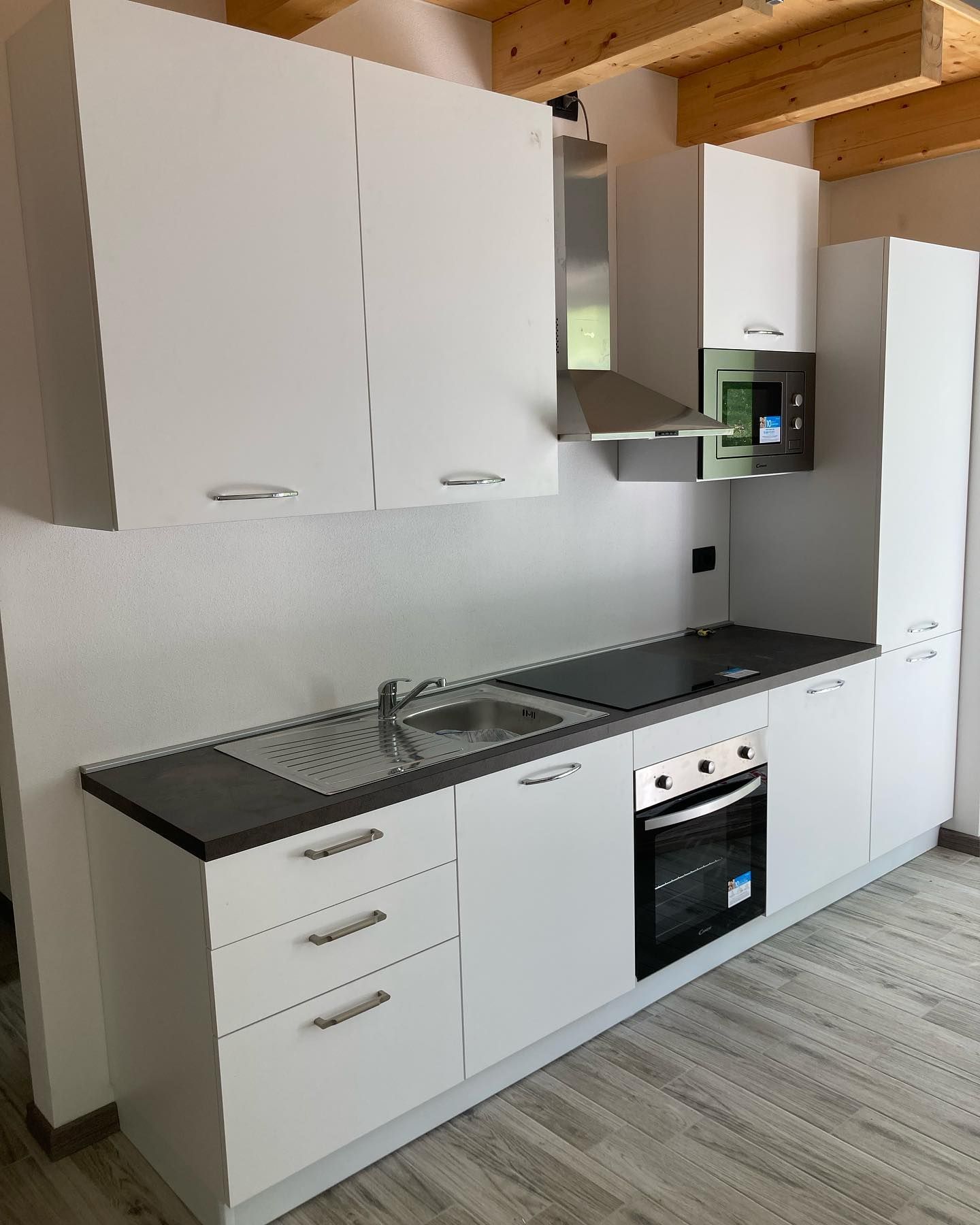 Una cucina con mobili bianchi ed elettrodomestici in acciaio inossidabile