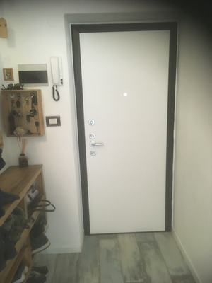 Una porta bianca in un corridoio con un telefono sul muro