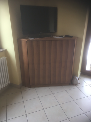 In una stanza c'è una TV appoggiata su un mobile di legno.